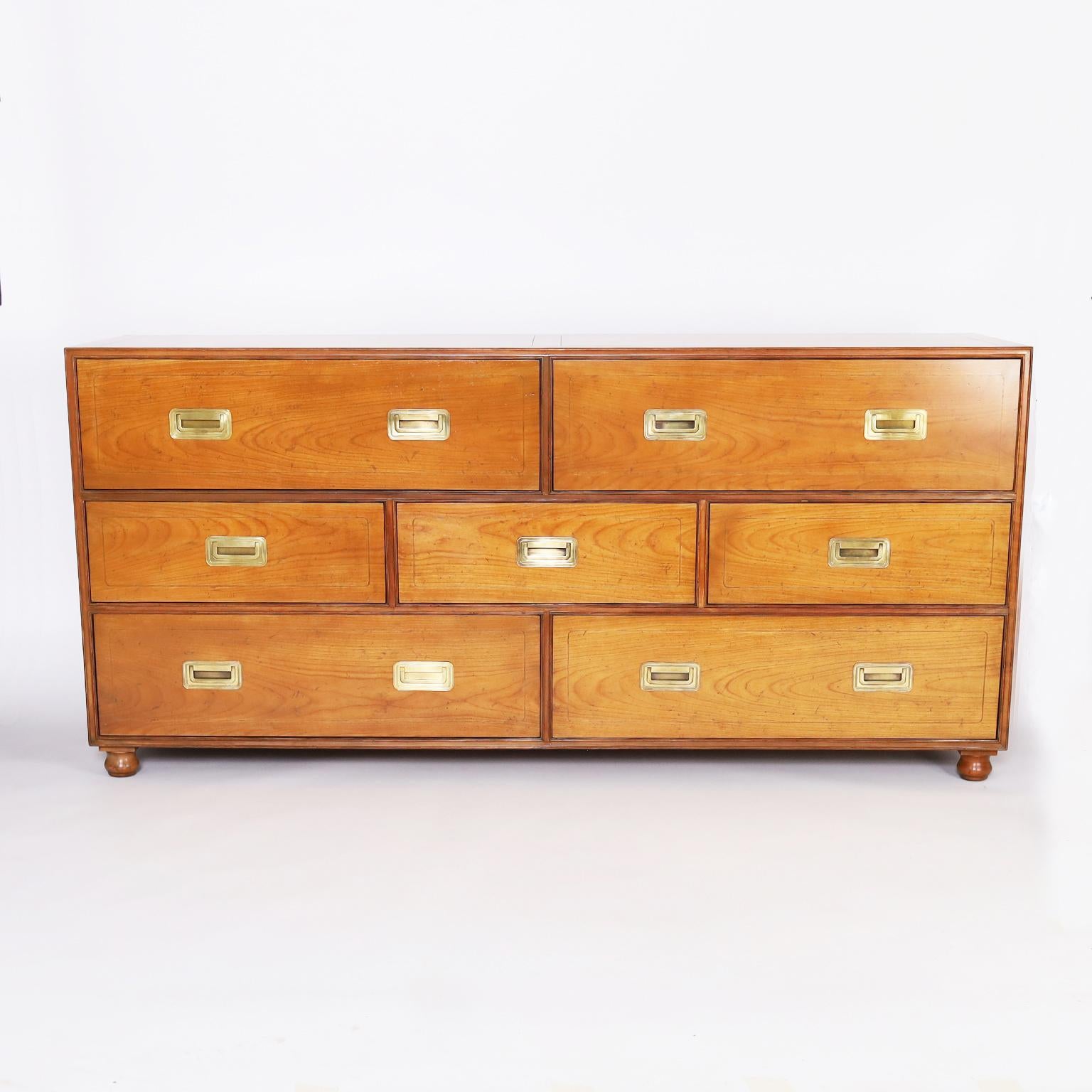 Handsome vintage campaign style chest or dresser crafted in fruitwood with seven drawers, brass hardware, and turned feet. Perfect marriage of modern and traditional design, signed Baker in a drawer.
