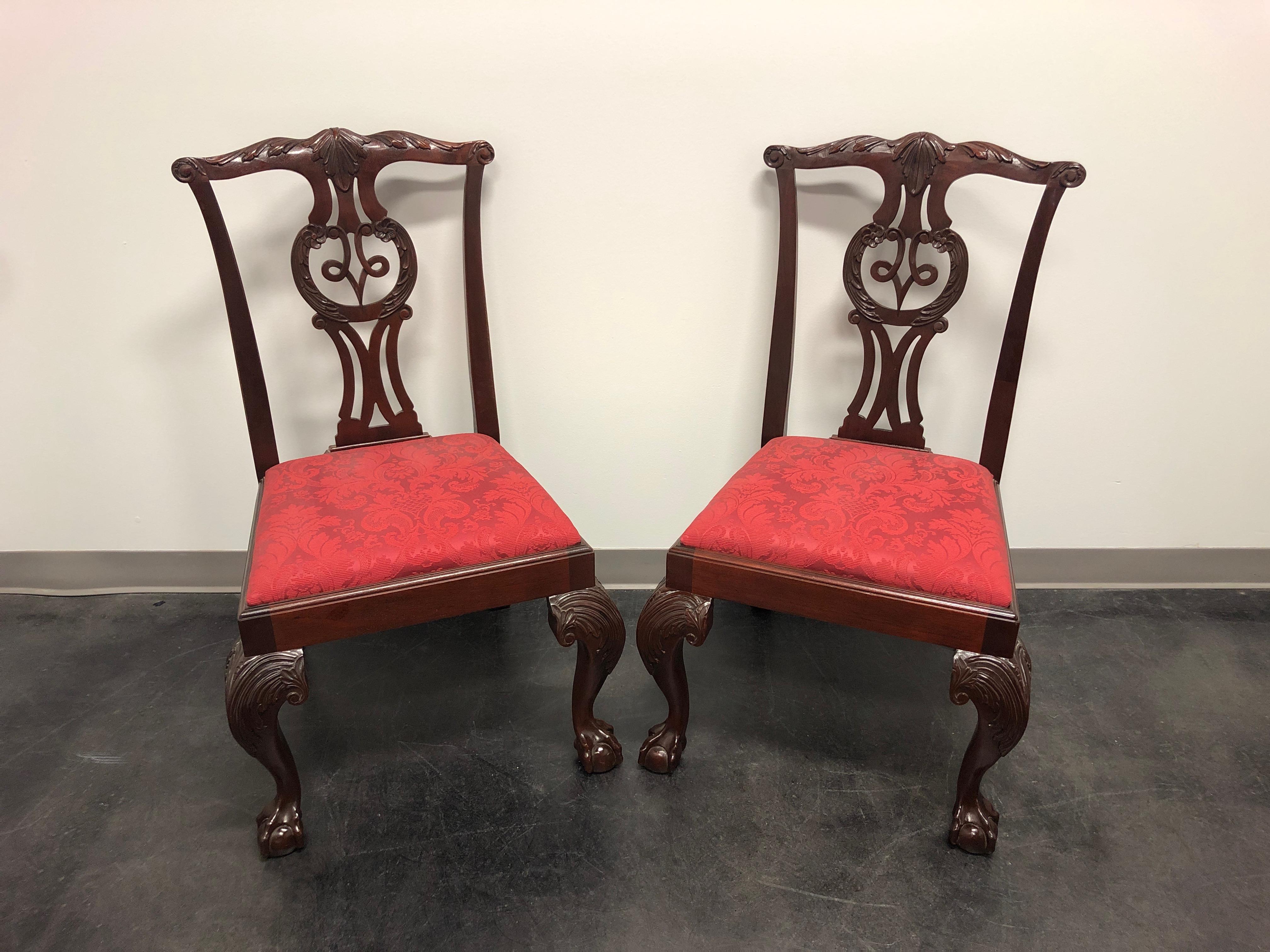 A pair of dining side chairs by Baker Furniture Company. Made in the USA in the late 20th Century. Solid Mahogany. Chippendale carved backsplats, cabriole legs with carved knees and ball in claw feet. 

Baker Model # 0-198

Measures: Overall: 24W