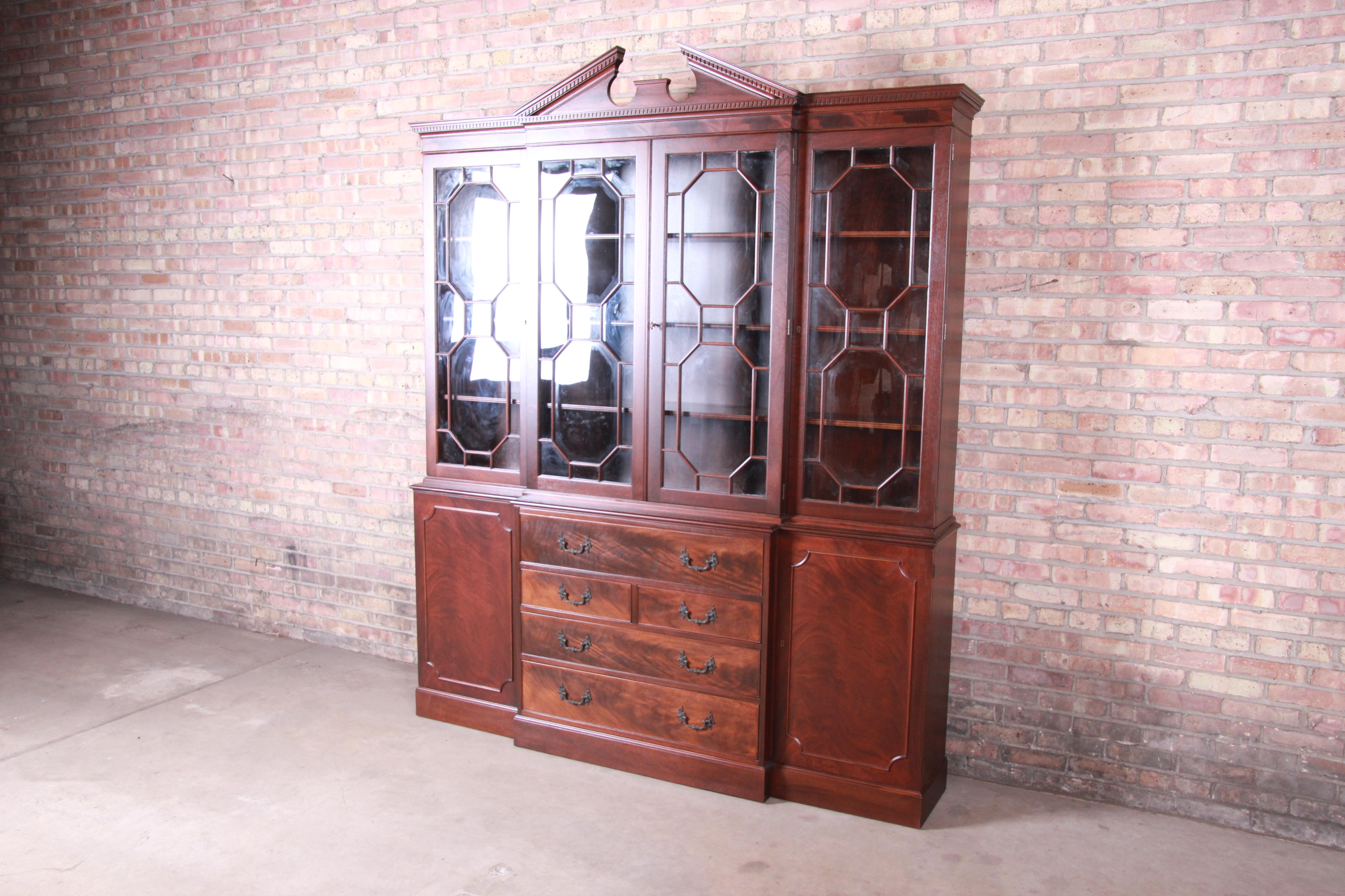 An exceptional flame mahogany Chippendale style breakfront bookcase or display cabinet with drop-down leather top secretary desk

By Baker Furniture

USA, circa 1960s

Measures: 75.25