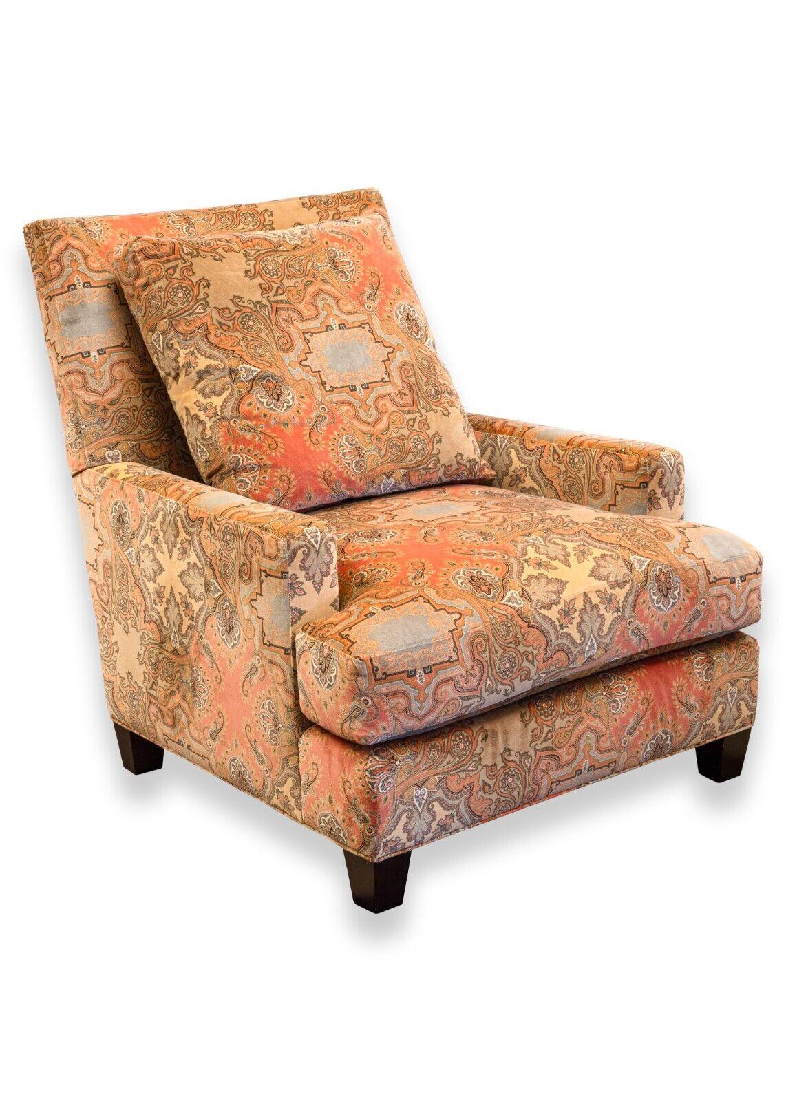 A Baker contemporary paisley upholstered armchair & ottoman. This is a magnificent armchair from furniture designer Baker. This piece is dressed in a lovely and eclectic paisley patterning. The paisley covers both the armchair and ottoman from head