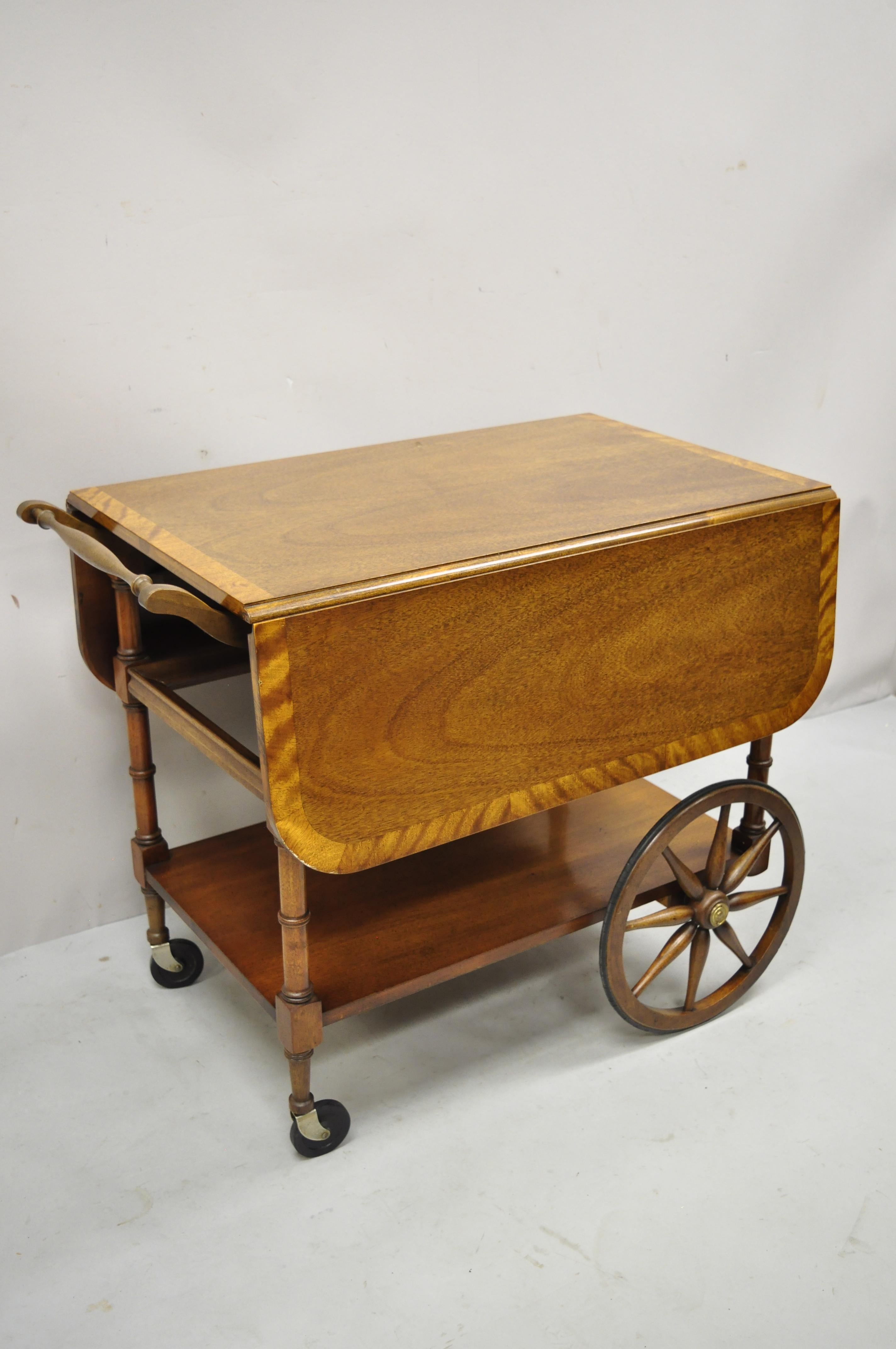 Baker Drop Leaf Mahagoni-Bandintarsie Teewagen Servierwagen mit ausziehbarem Glastablett. Der Artikel verfügt über eine satinierte Holzeinlage, eine untere abnehmbare Glasablage, eine schöne Holzmaserung, ein Originaletikett, 1 Schublade mit