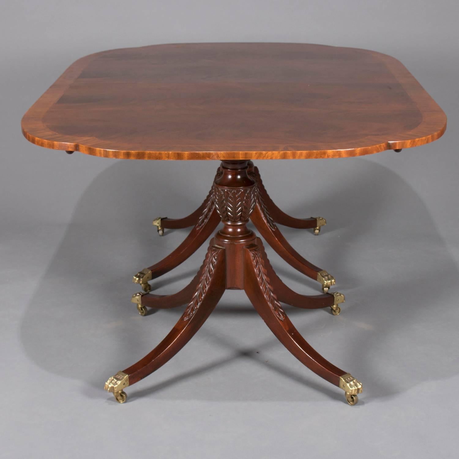 Duncan Phyfe School flame mahogany Historic Charleston reproduction double pedestal dining table features banded top raised on tow urn form pedestals with three acanthus carved legs terminating in cast bronze paw feet with casters, includes single
