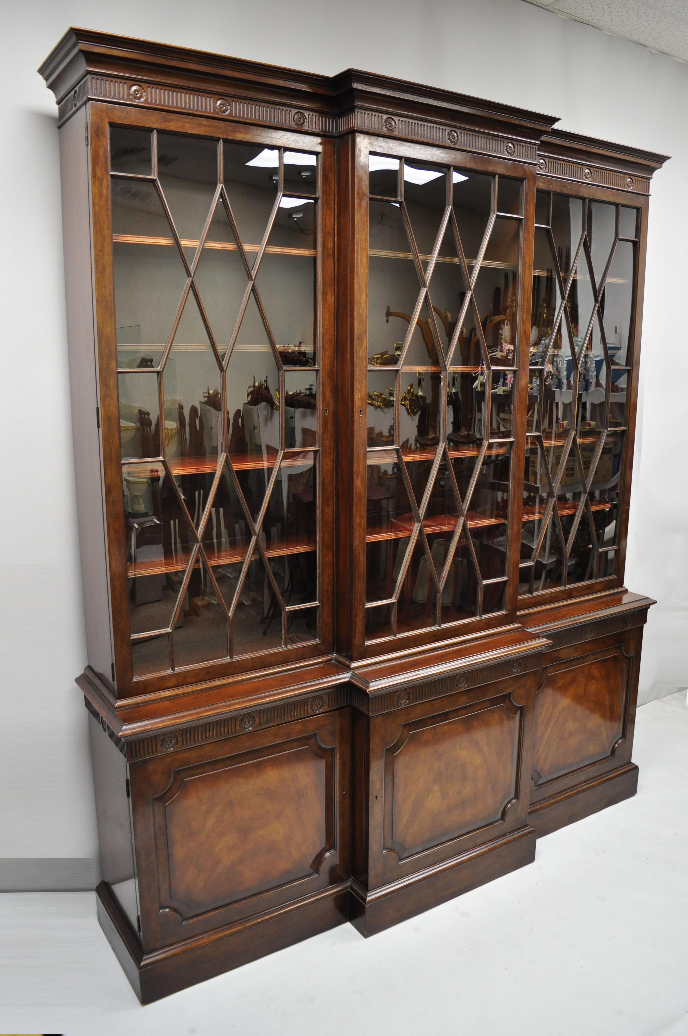 Baker English Regency style mahogany breakfront China cabinet bookcase. Item features individual panes of glass, solid wood construction, beautiful wood grain, nicely carved, 2 part construction, 6 swing doors, original label, working lock and key,