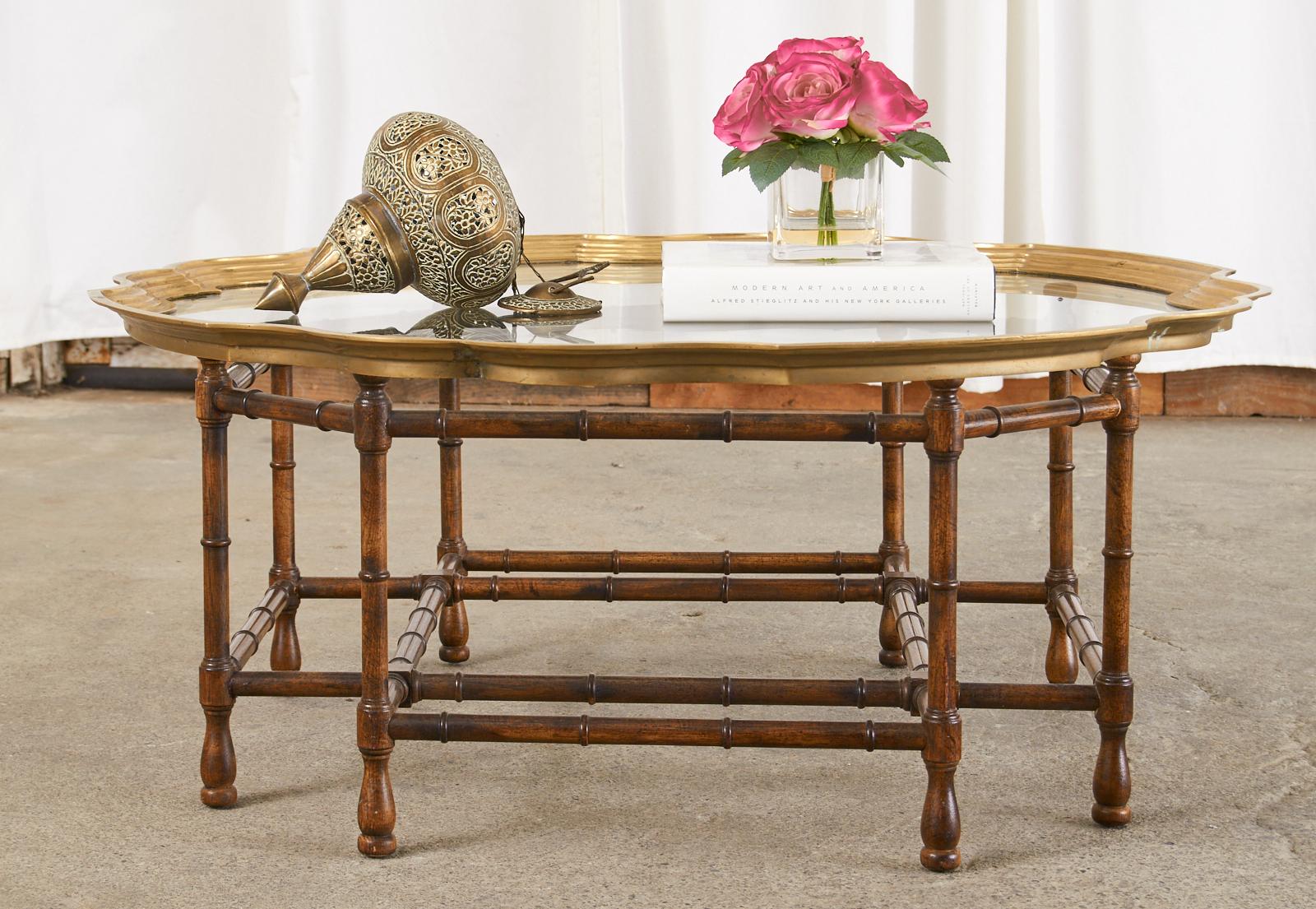 Hollywood regency brass and glass tray top coffee or cocktail table with dramatic scalloped edges framing the pane of glass. The mid-century modern table has a geometric octagonal shaped faux bamboo wood base with a beautiful open design. The tray