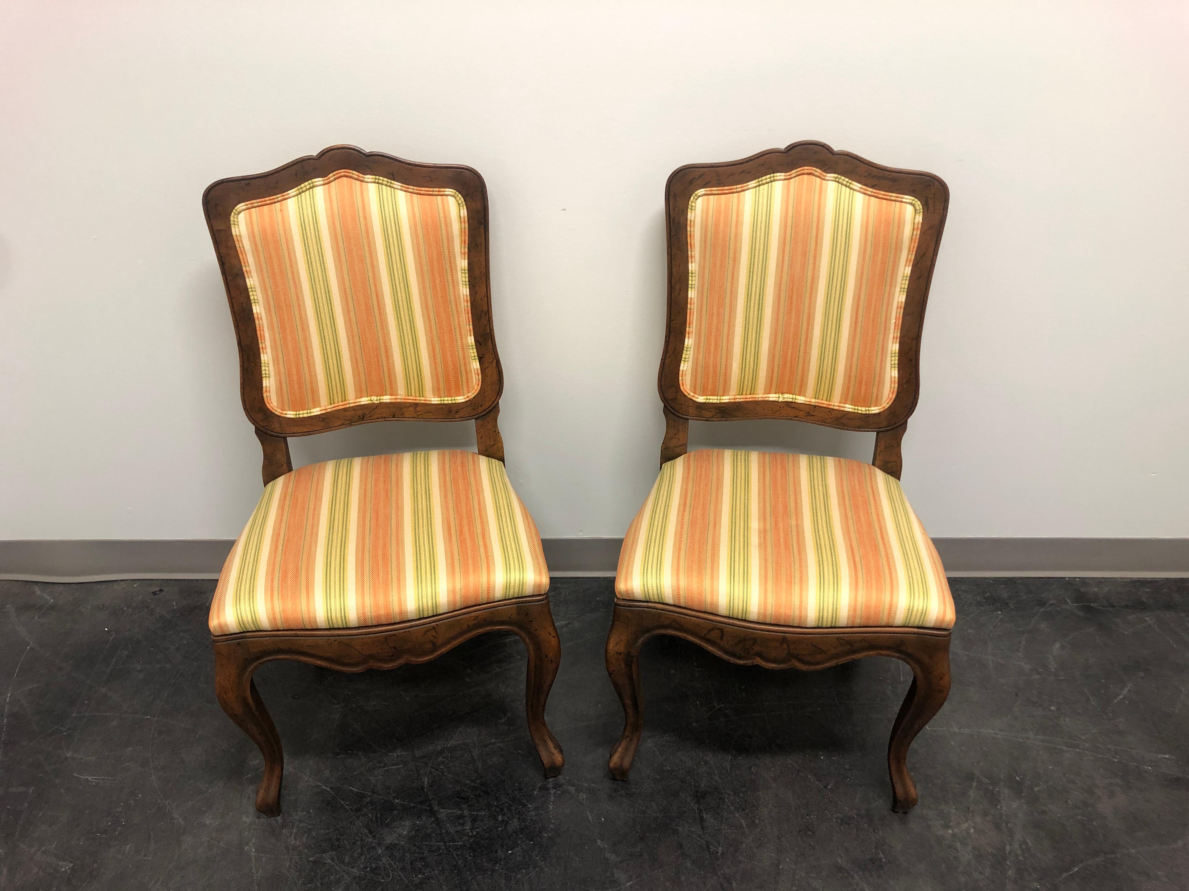 A pair of French Country style dining side chairs by Baker Furniture Company. Walnut with a distressed finish, curved legs, stripe fabric upholstered backs and seats. Made in the USA, in the late 20th Century.
 
Measures: Overall: 20 W 20 D 37 H,