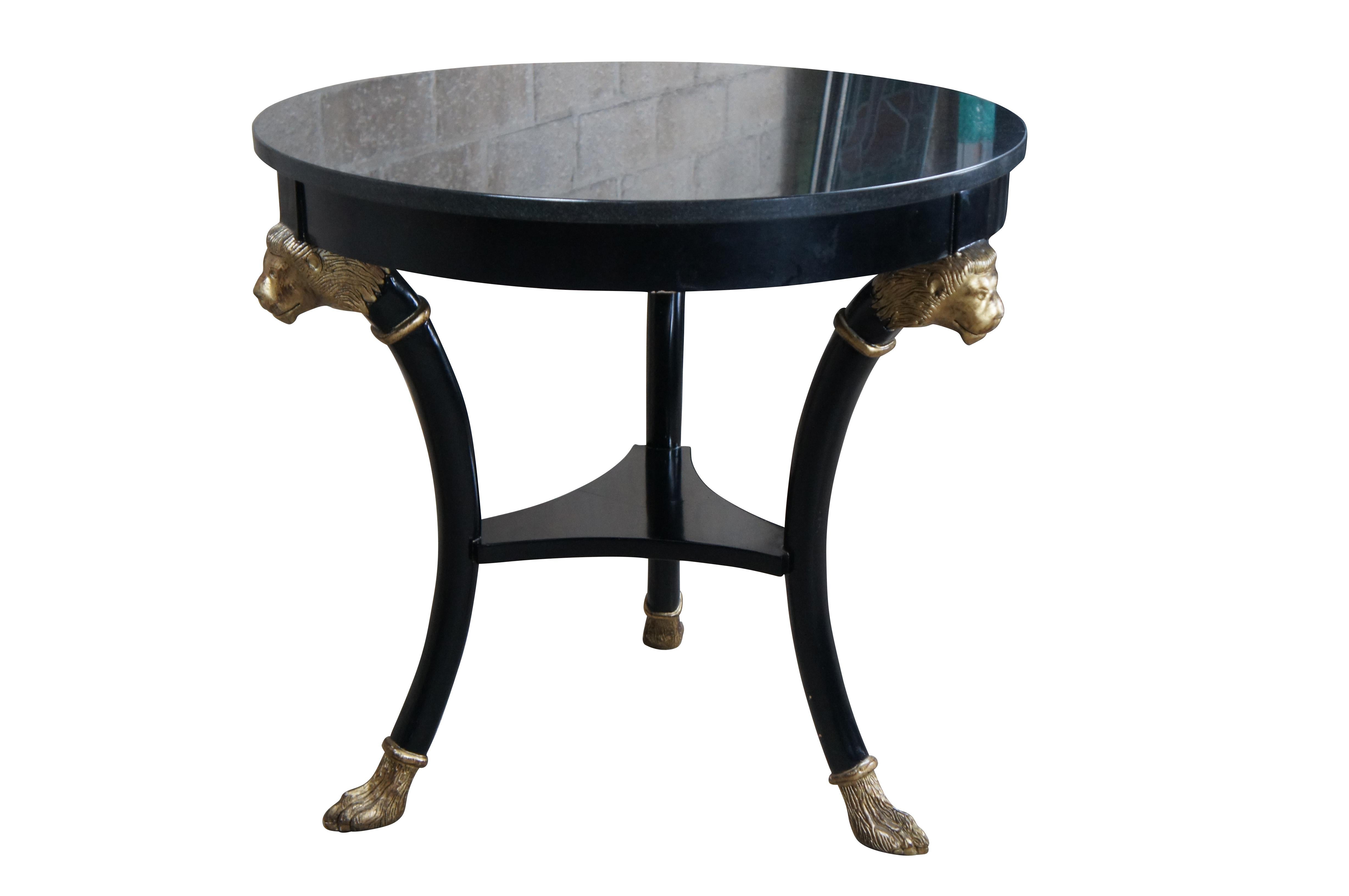 Late 20th Century Baker Furniture Empire / Regency / Neoclassical inspired Gueridon side table. Features a hardwood ebonized frame with dark granite top. The round form is supported by three contoured legs with gold finished lion heads beneath the