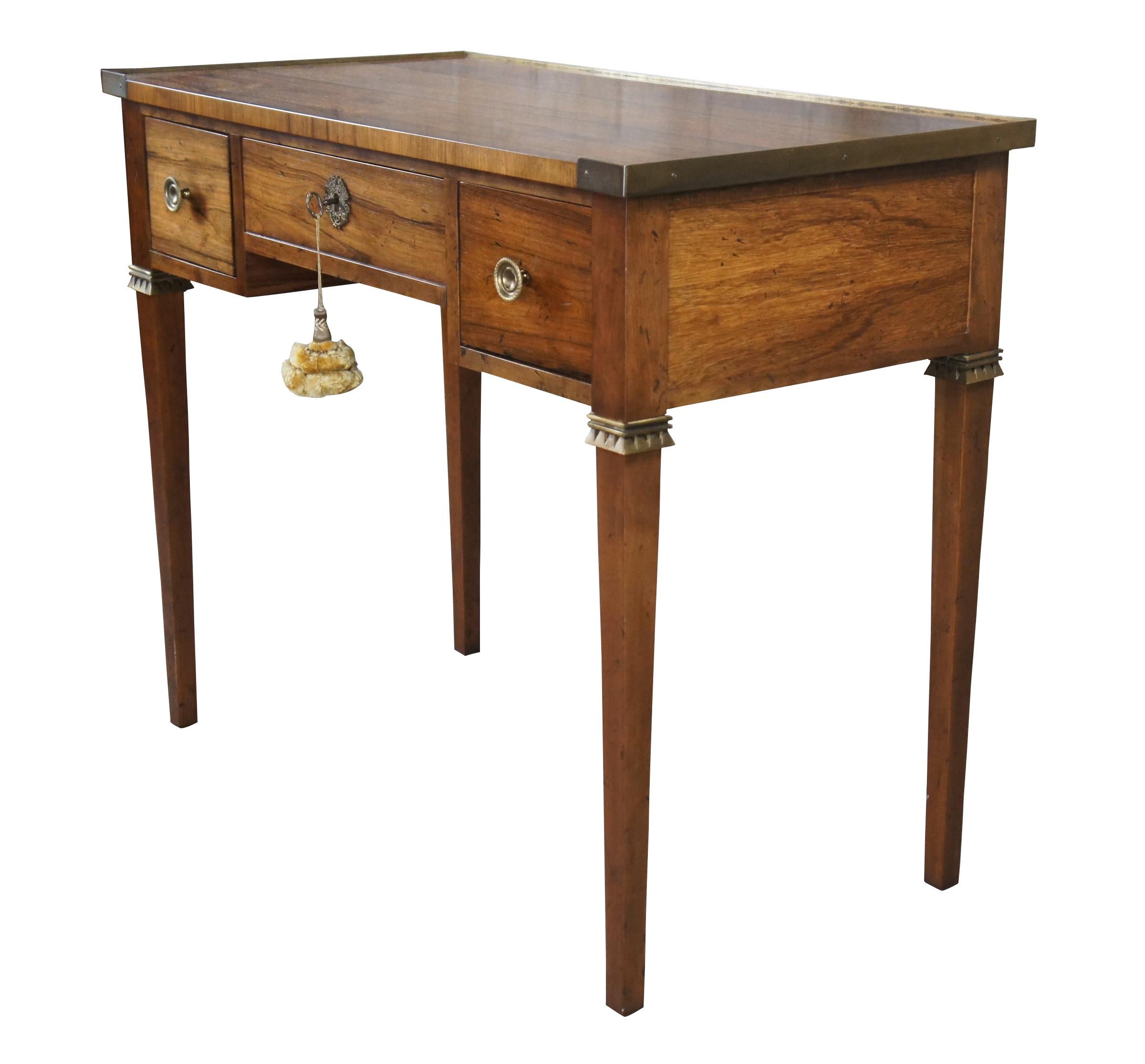 A stunning 1960s French Louis XVI or neoclassical style ladies desk / receiving table by Michael Taylor for Baker Furniture Inc. Features a rectangular top with brass banding over a frieze fitted with three dovetailed drawers, decorated with ornate