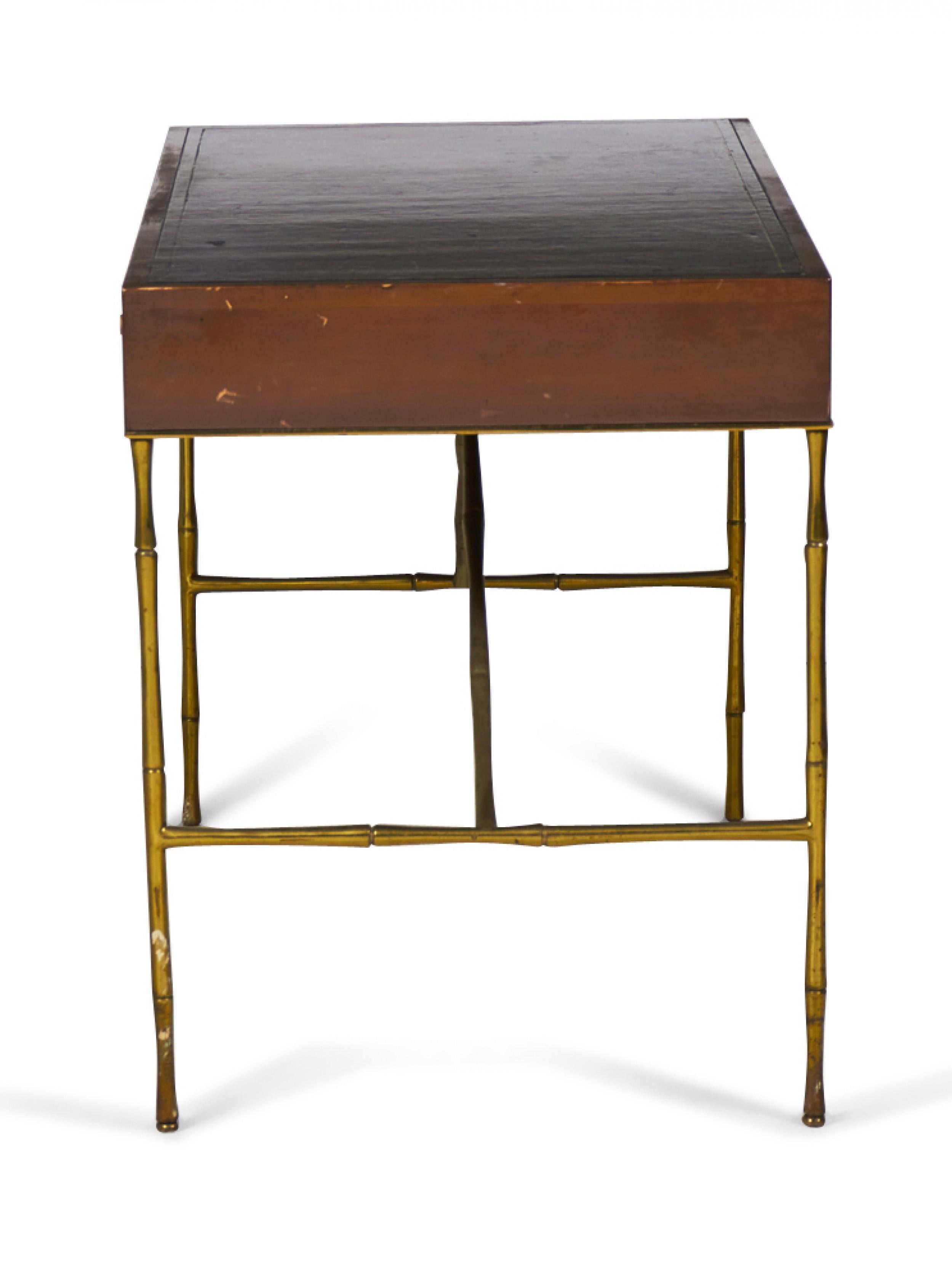 American Mid-Century walnut desk with a black leather top and three drawers with rounded wooden drawer pulls, resting on four stretcher-connected brass faux bamboo legs. (BAKER FURNITURE CO.).