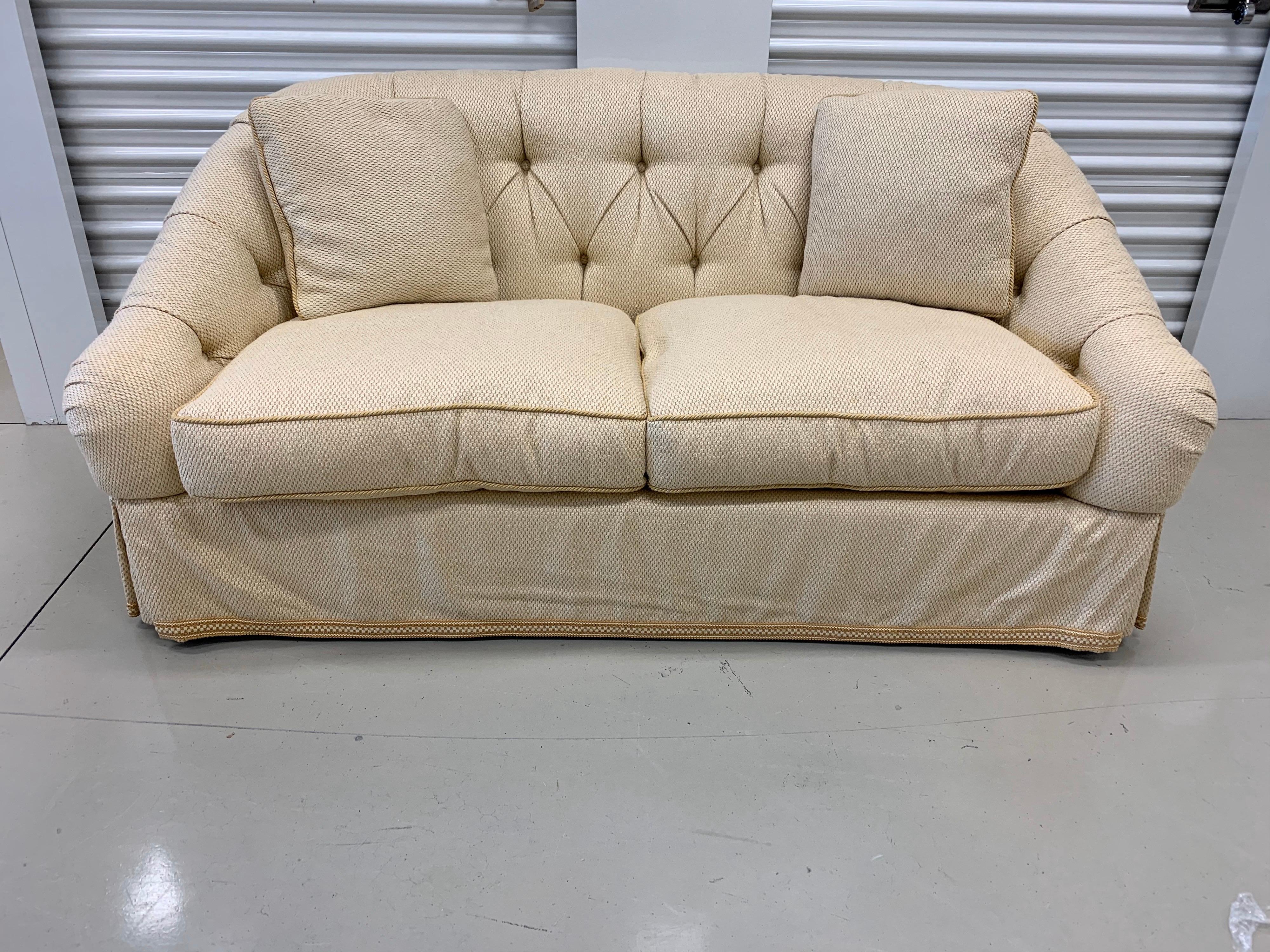 Elegant beige upholstered loveseat by US furniture maker Baker Furniture. Great tufted look and a color that will remain neutral in any home.