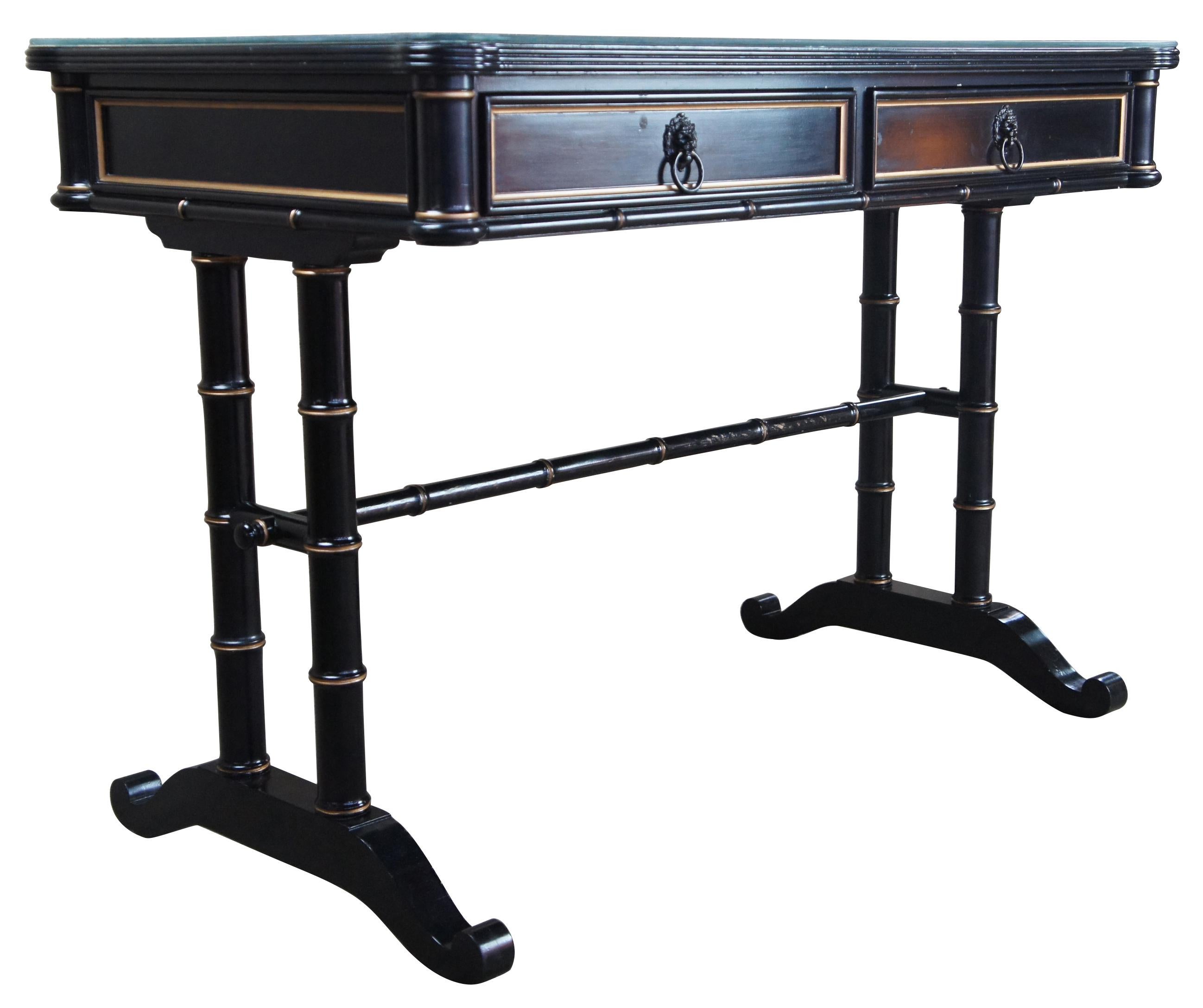 Baker Furniture black lacquer gold campaign writing desk library accent table

Baker Furniture black and gold writing desk. Features a faux bamboo styling, two drawers with lion head pulls, glass covered top.