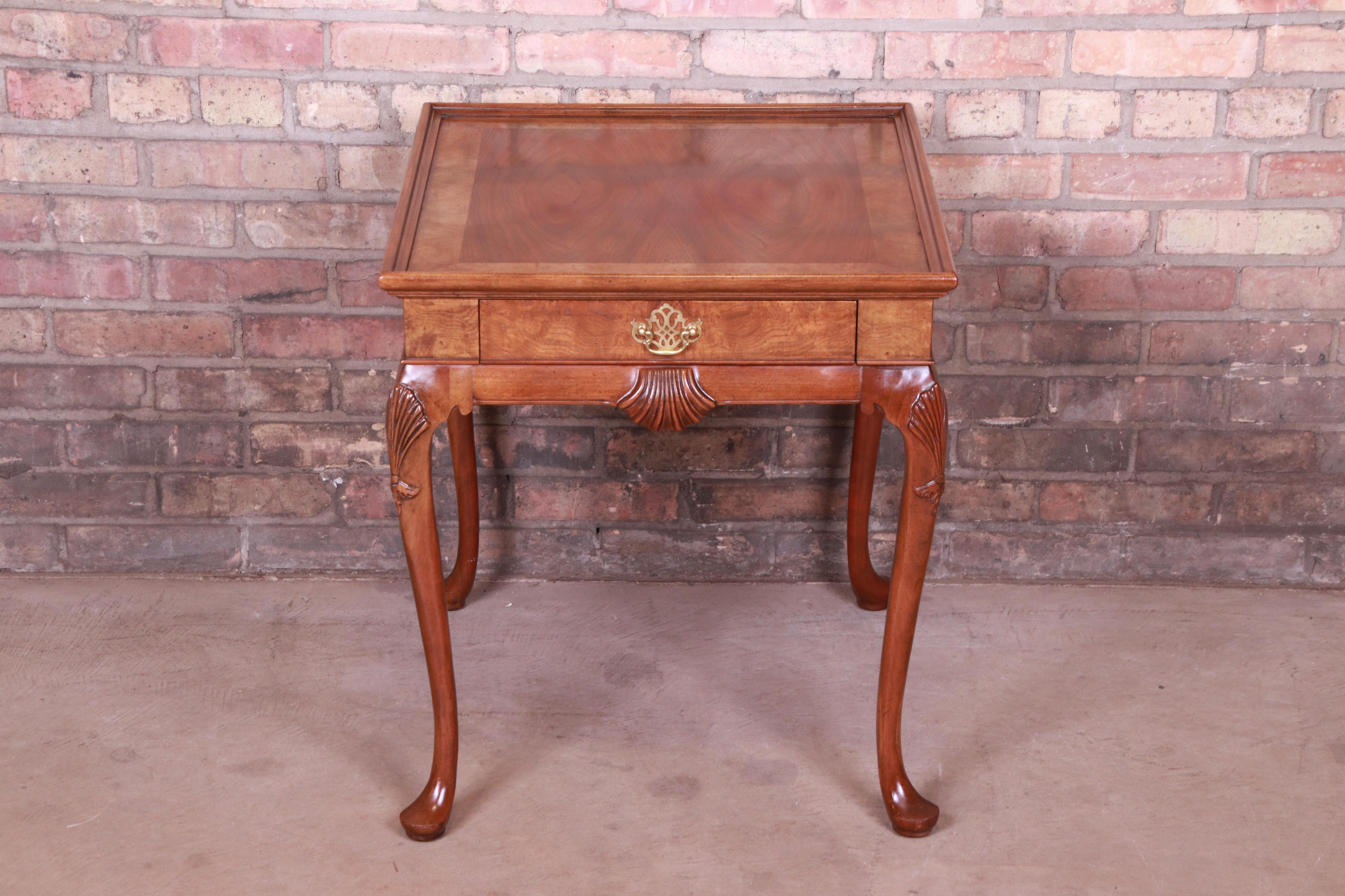 A gorgeous traditional Queen Anne style single drawer nightstand or side table

By Baker Furniture

USA, circa 1980s

Book-matched walnut top, carved solid walnut legs with shell motif, burl wood drawer front and trim, and original brass