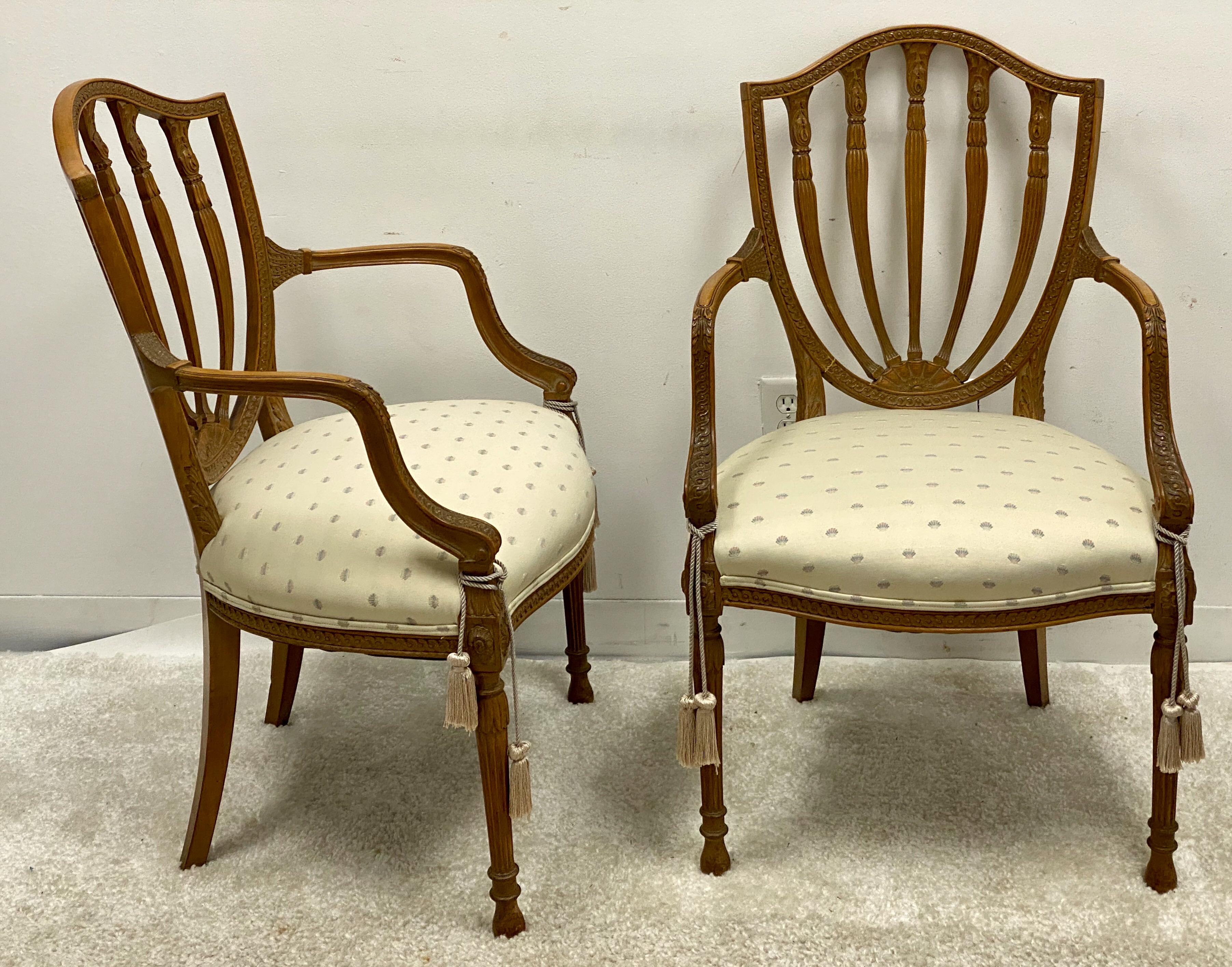 This is a pair of carved fruitwood Adam style shieldback chairs by Baker Furniture. They are marked and in very good condition. The upholstery is vintage but free of stains and tears.