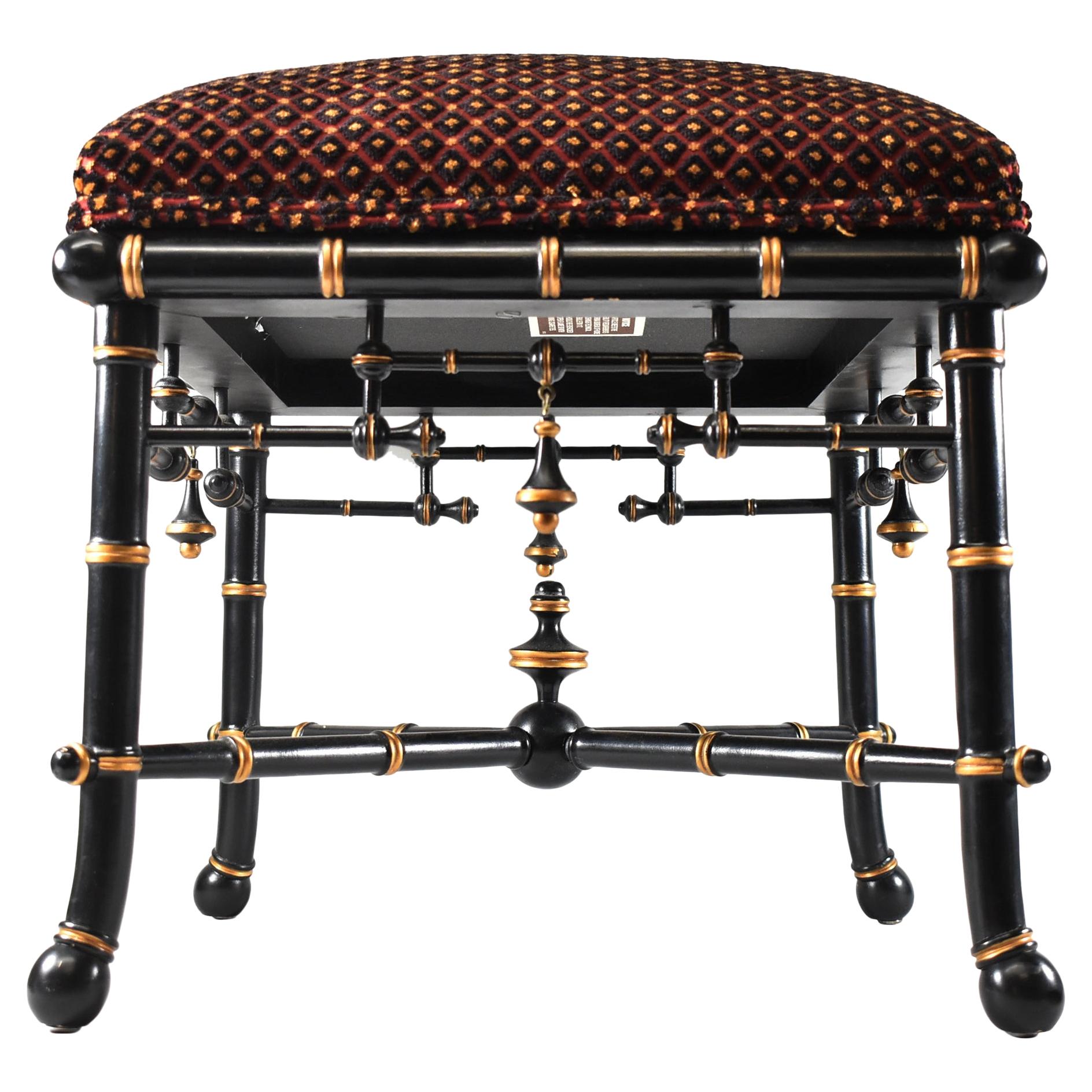Baker furniture chinoiserie foot stool. Black lacquer bamboo look frame with gold highlights. Burgundy, black and gold patterned fabric. Measures: 16