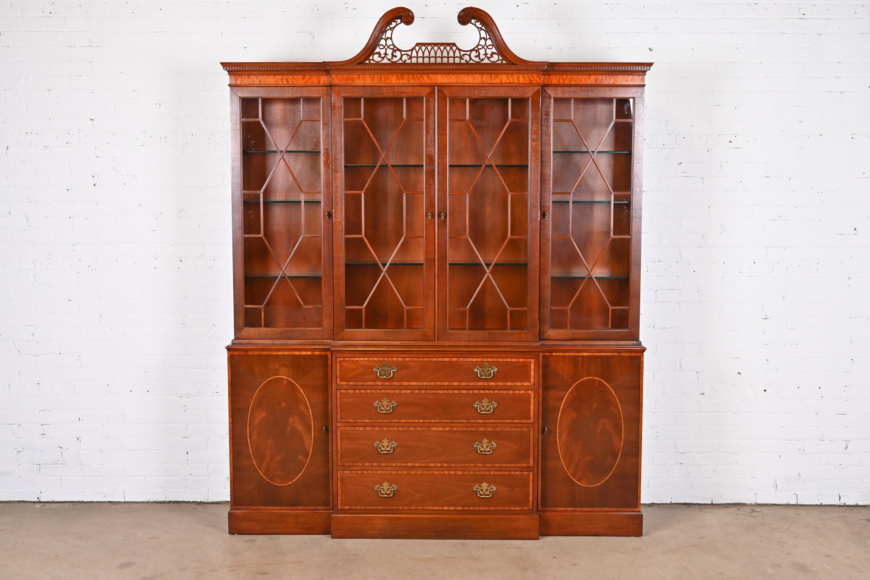 A gorgeous Georgian or Chippendale style lighted breakfront bookcase cabinet or dining cabinet

By Baker Furniture

USA, Circa 1980s

Flame mahogany, with satinwood banding, mullioned glass front doors, and original brass
