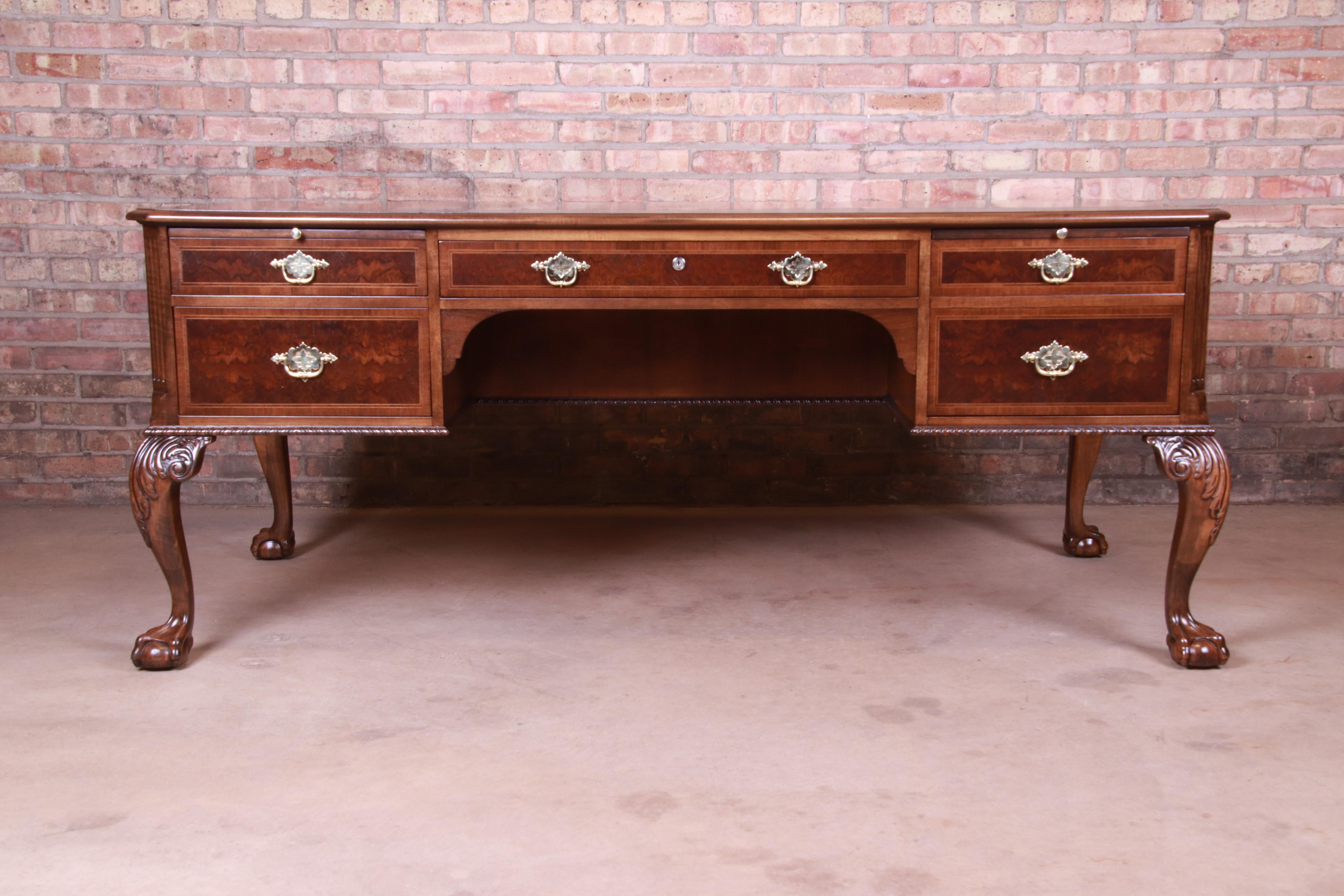 An exceptional English Chippendale style executive desk

By Baker Furniture

USA, circa 1980s

Book-matched walnut top, carved solid walnut cabriole legs with ball and claw feet, burled walnut drawer fronts, and original brass