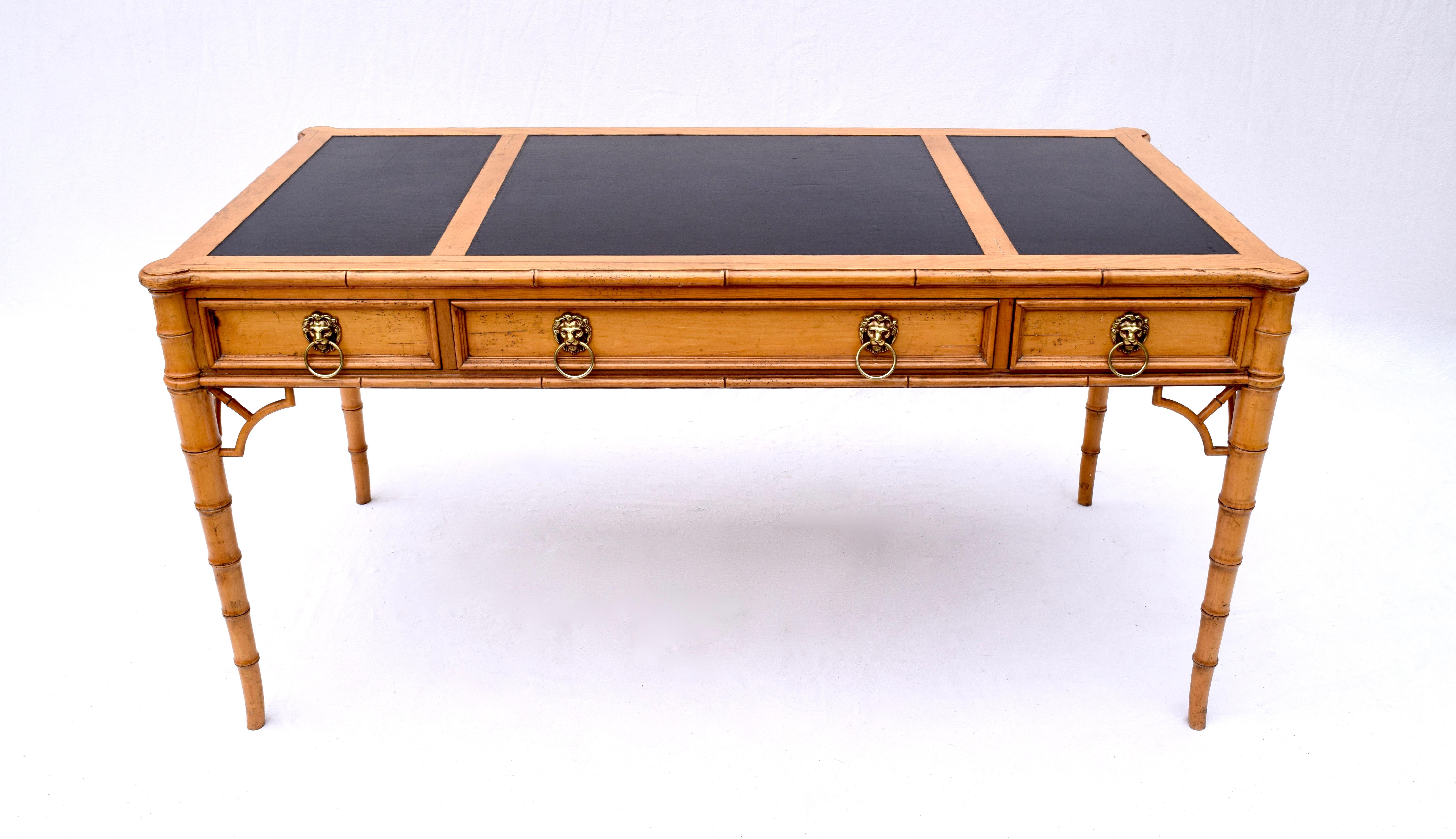 An exceptional Baker Furniture Chippendale & Regency influenced faux bamboo desk featuring three dovetailed drawers, brass lion head pulls and mock drawers on the opposite side. Patinated solid pine construction with tooled leather & scalloped