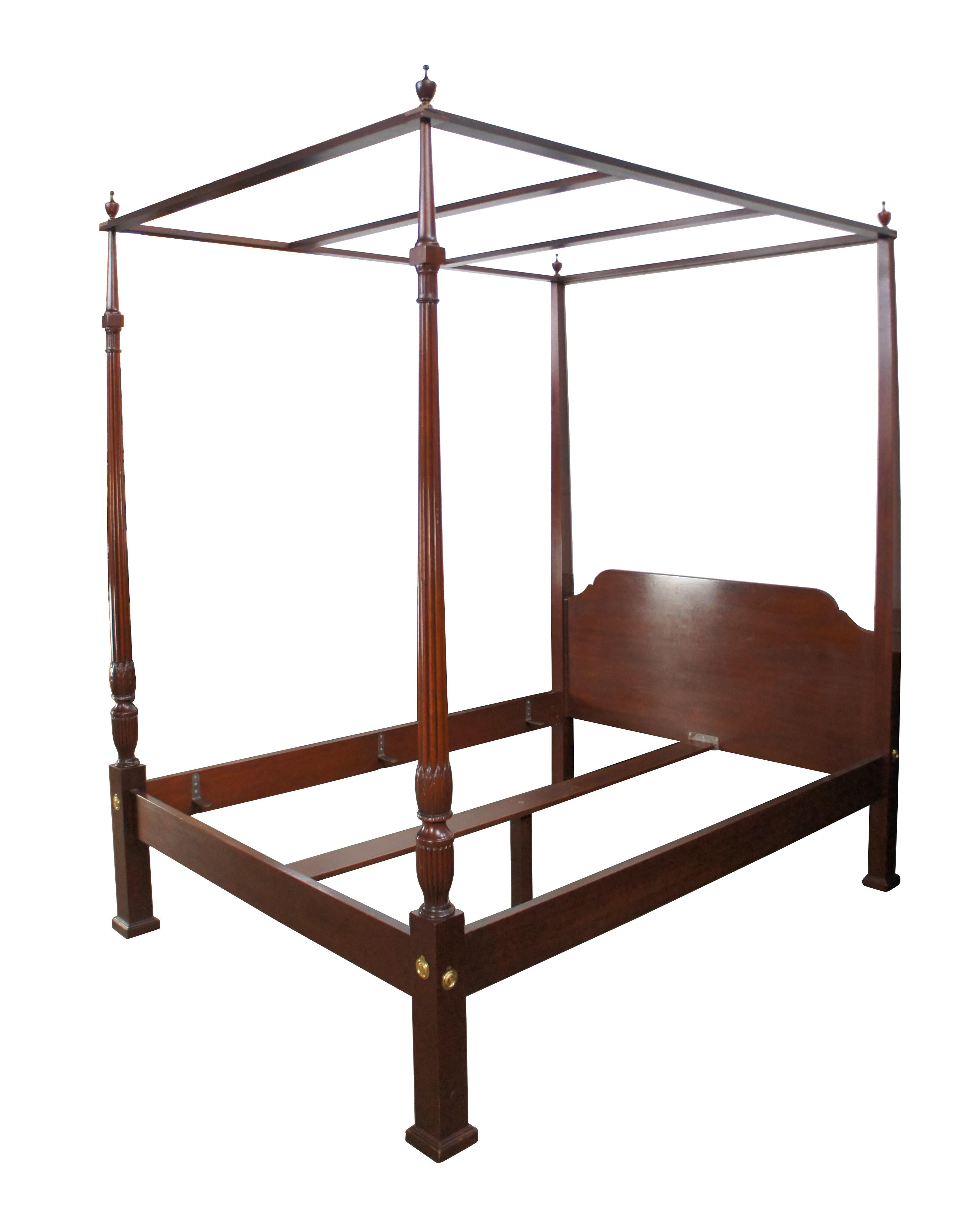 Un maestoso letto a baldacchino Colonial Williamsburg di Baker Furniture, CIRCA anni '80.  Presenta una struttura in mogano massiccio con montanti ribassati, baldacchino con terminali a trofeo e gambe con piedi quadrati con accenti in ottone. 