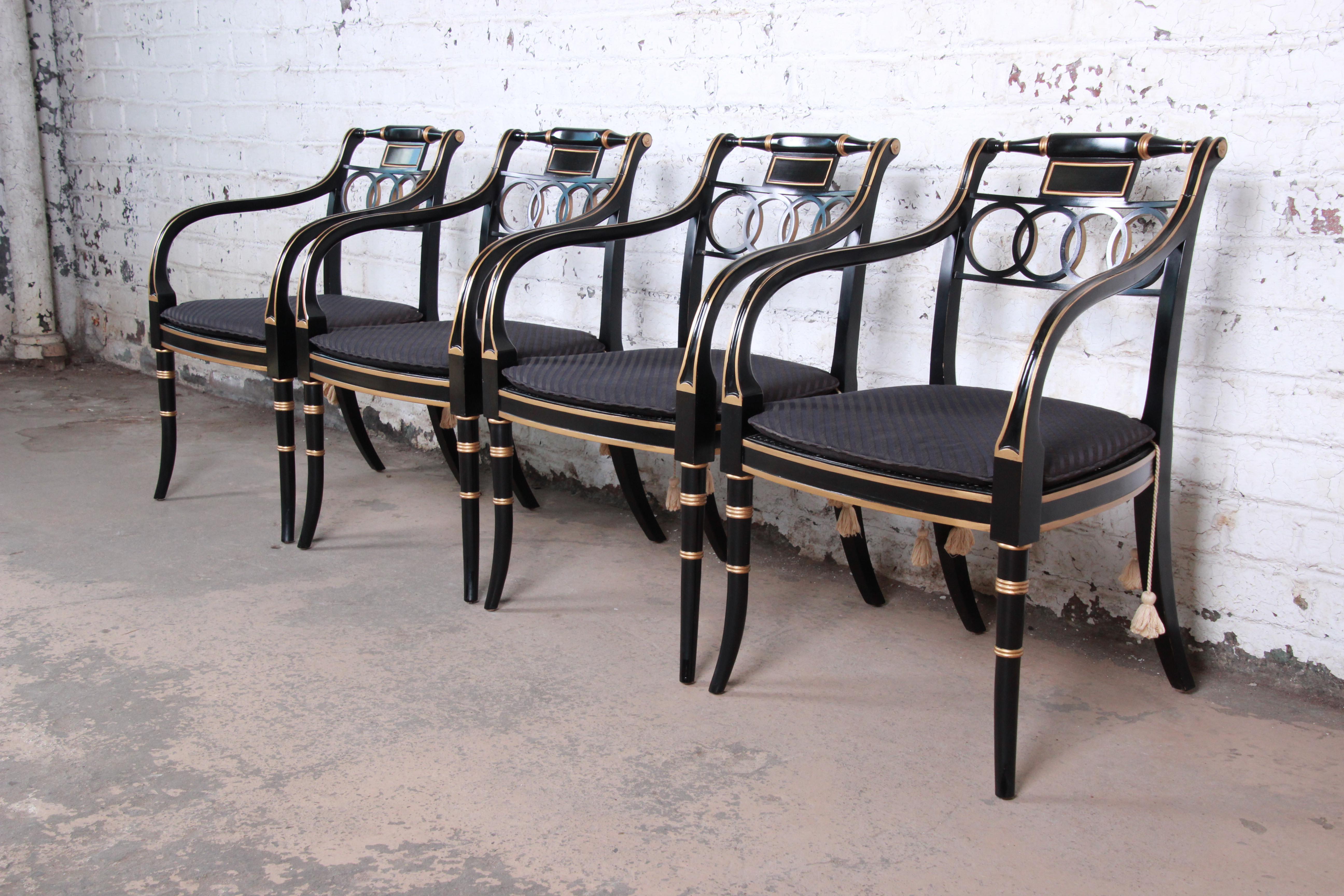 An exceptional set of four Regency style armchairs from the Historic Charleston collection by Baker Furniture. The chairs feature stunning ebonized and gold gilt solid wood frames with caned seats and removable seat cushions. Made with the highest