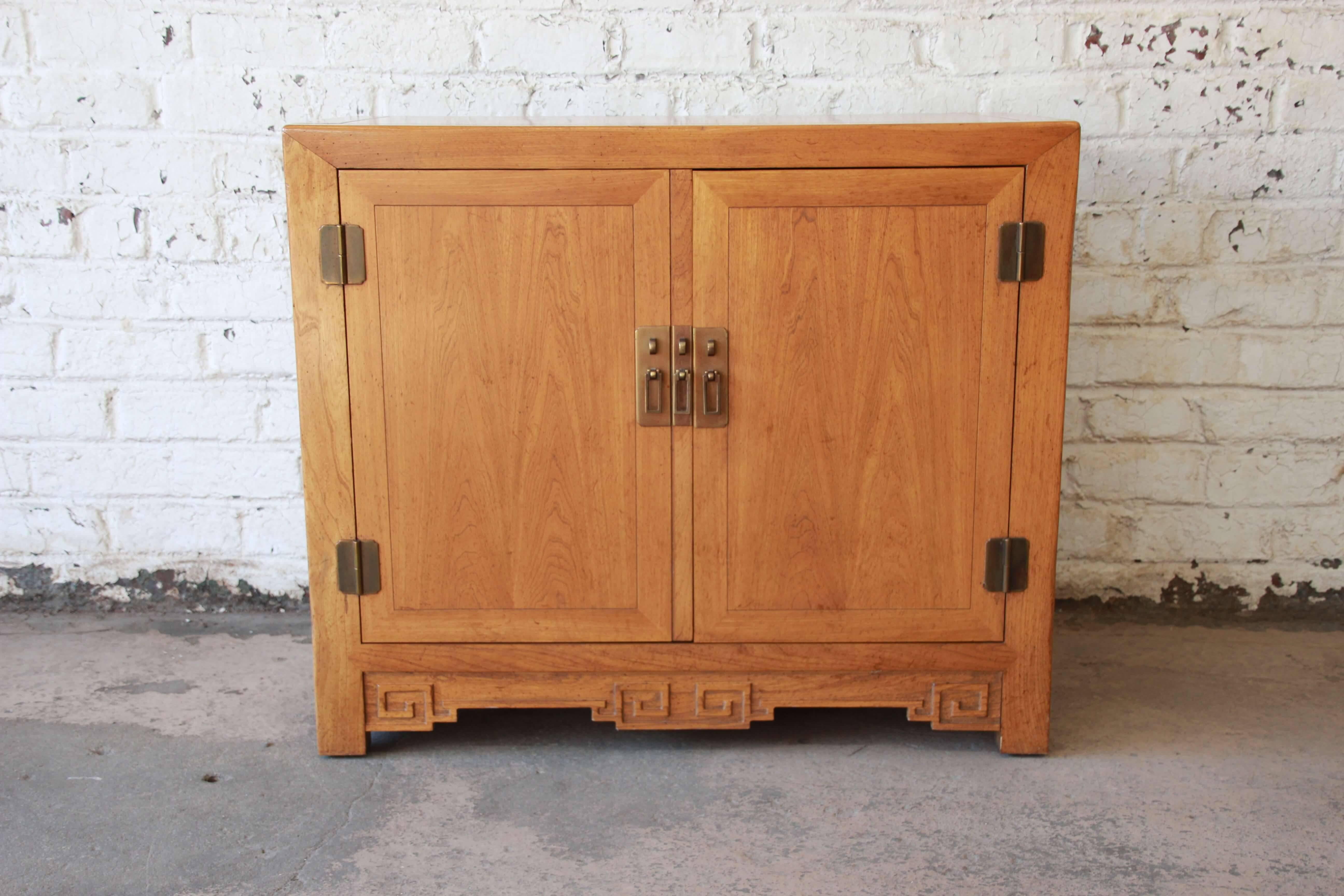 Offering a very nice Baker Furniture elm wood chinoiserie server or butler's stand. The piece has beautiful Asian inspired hardware and carvings. The two cabinet doors open up to a large drawer and a shelf for storage. This piece is made from solid