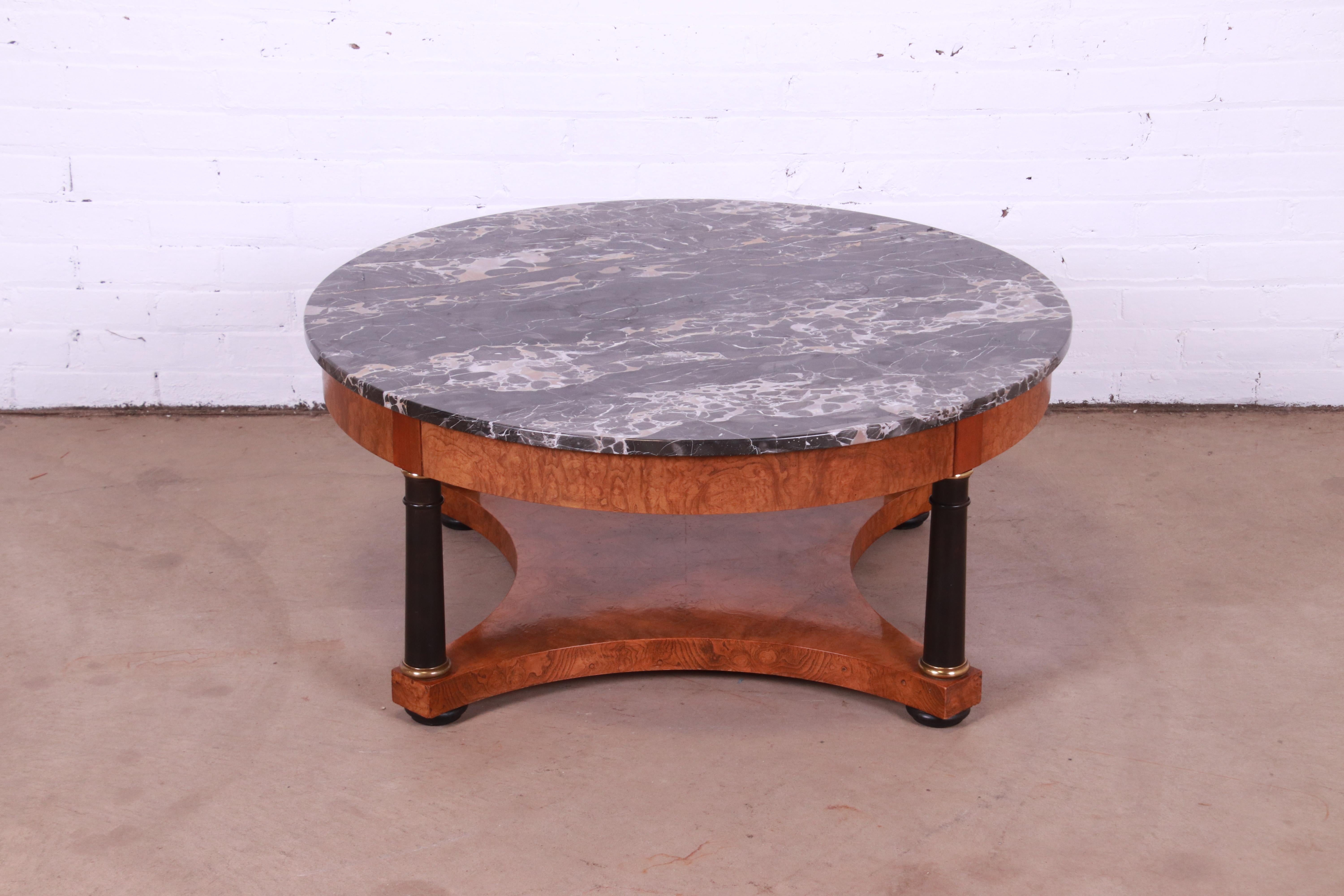A gorgeous Empire or Neoclassical style coffee or cocktail table

By Baker Furniture

USA, Circa 1980s

Burl wood, with Italian marble top, ebonized columns, and brass accents.

Measures: 38