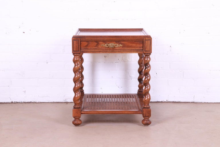 A gorgeous Jacobean style English barley twist tea table or occasional side table 

By Baker Furniture

USA, Circa 1970s

Carved oak, with caned lower shelf and original brass hardware.

Measures: 21