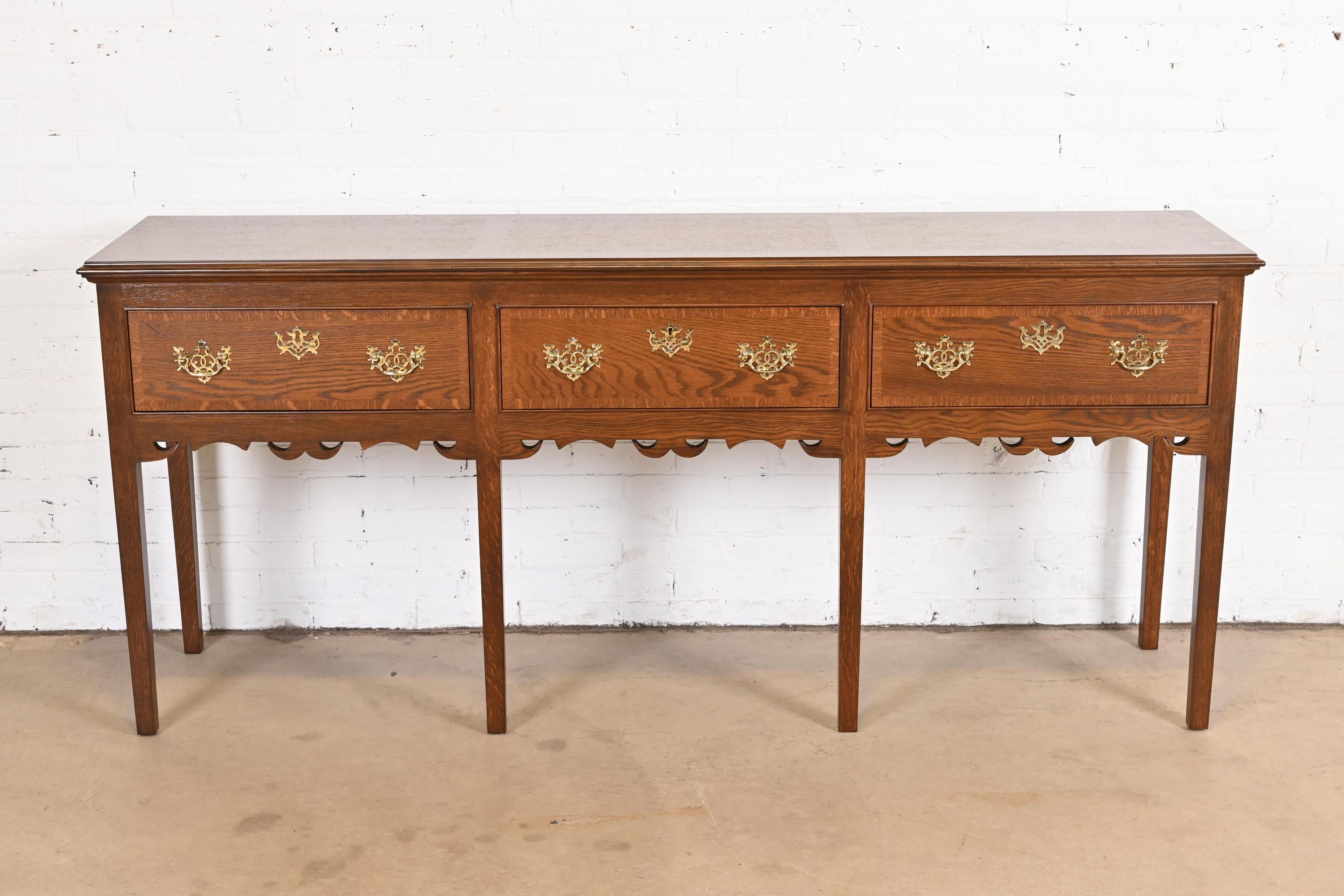 An exceptional English Georgian style sideboard, credenza, or hunt board
By Baker Furniture
USA, circa late 20th century.
Carved banded quarter sawn oak, with original brass hardware. Middle drawer locks, and original key is included.
Measures: 80