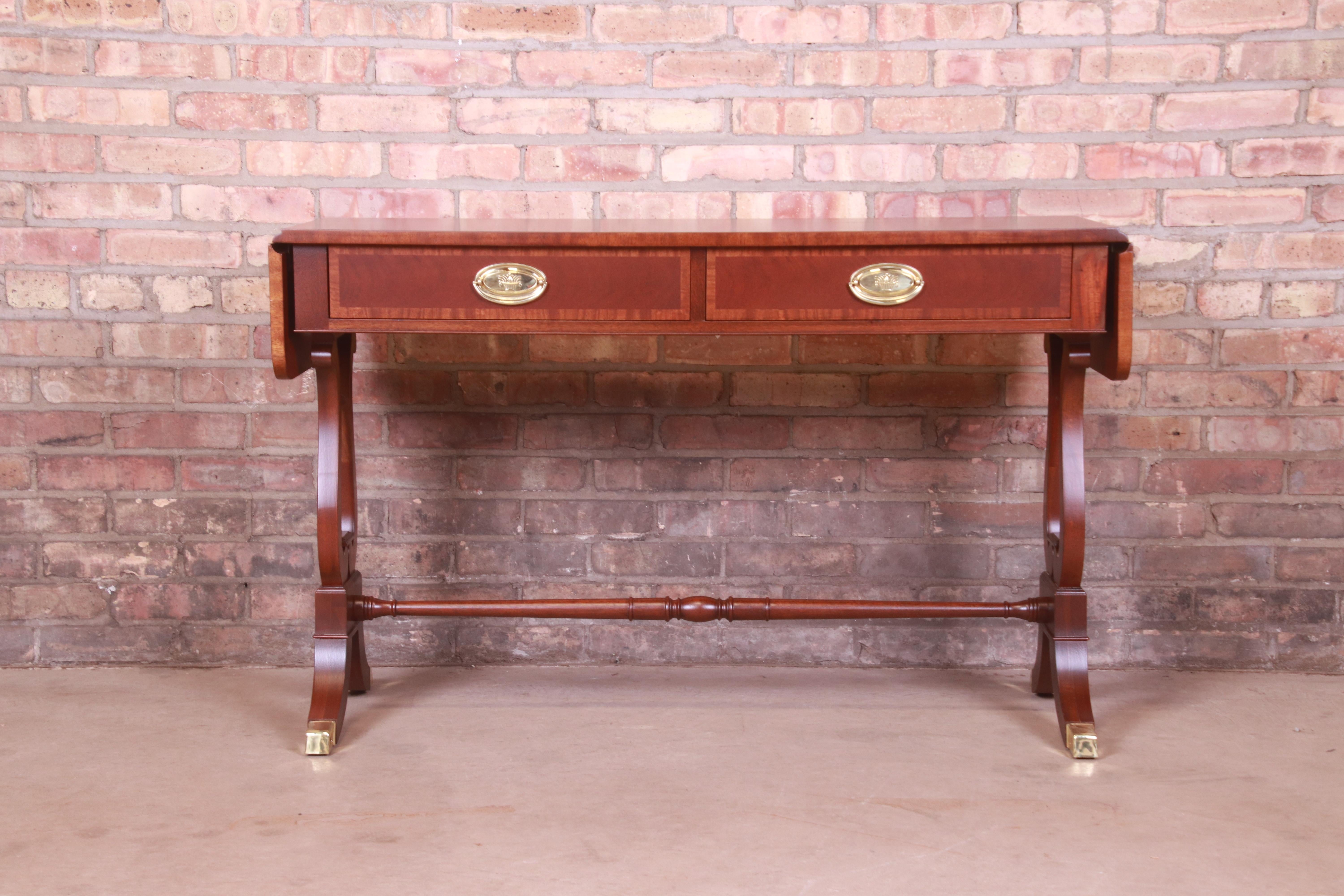 A gorgeous English Regency or Georgian style console table or sofa table

By Baker Furniture

USA, Circa 1980s

Banded mahogany, with brass accents, brass-capped feet, and original brass hardware.

Measures: 45.25