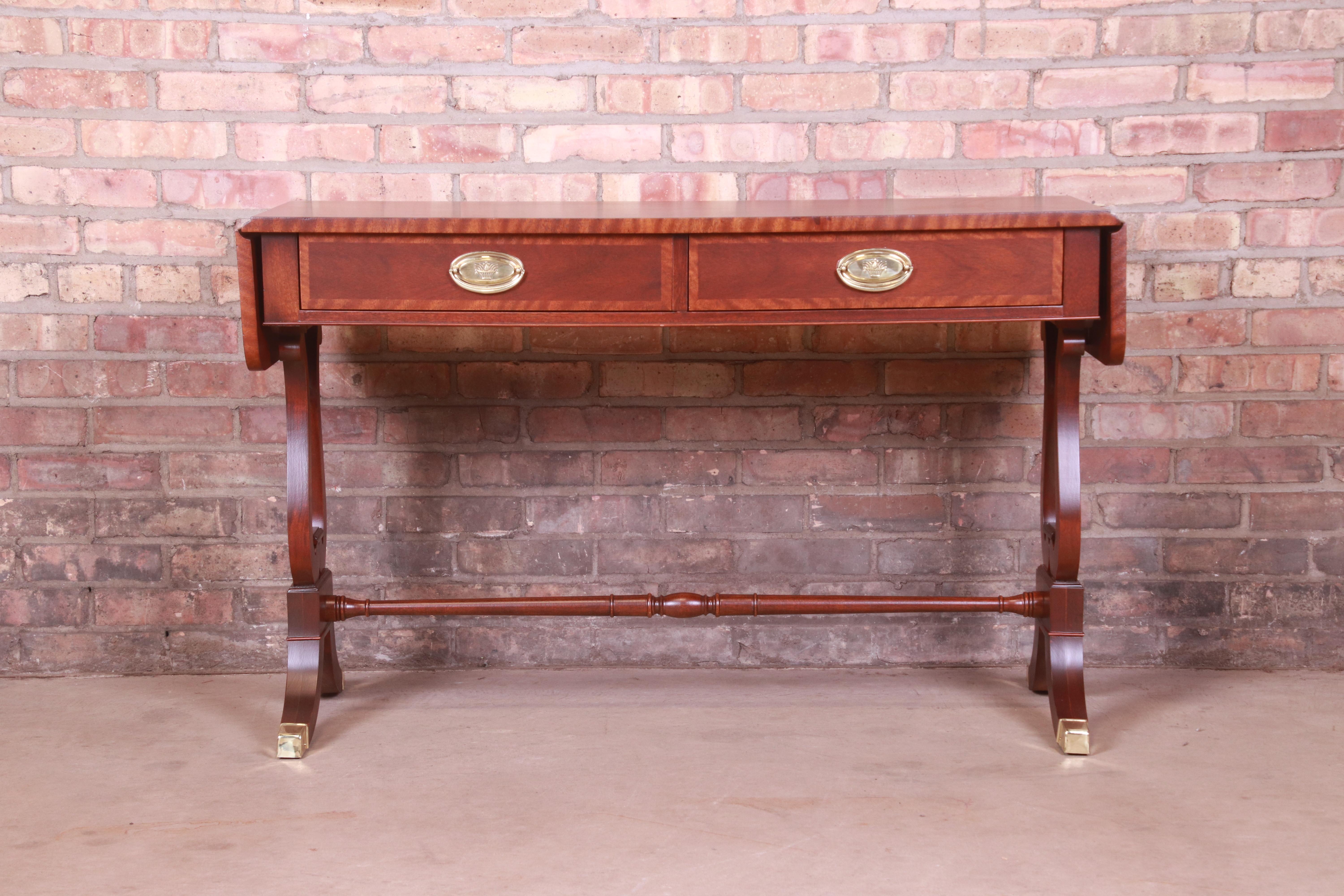 A gorgeous English Regency or Georgian style console table or sofa table

By Baker Furniture

USA, Circa 1980s

Banded mahogany, with brass accents, brass-capped feet, and original brass hardware.

Measures: 45.25
