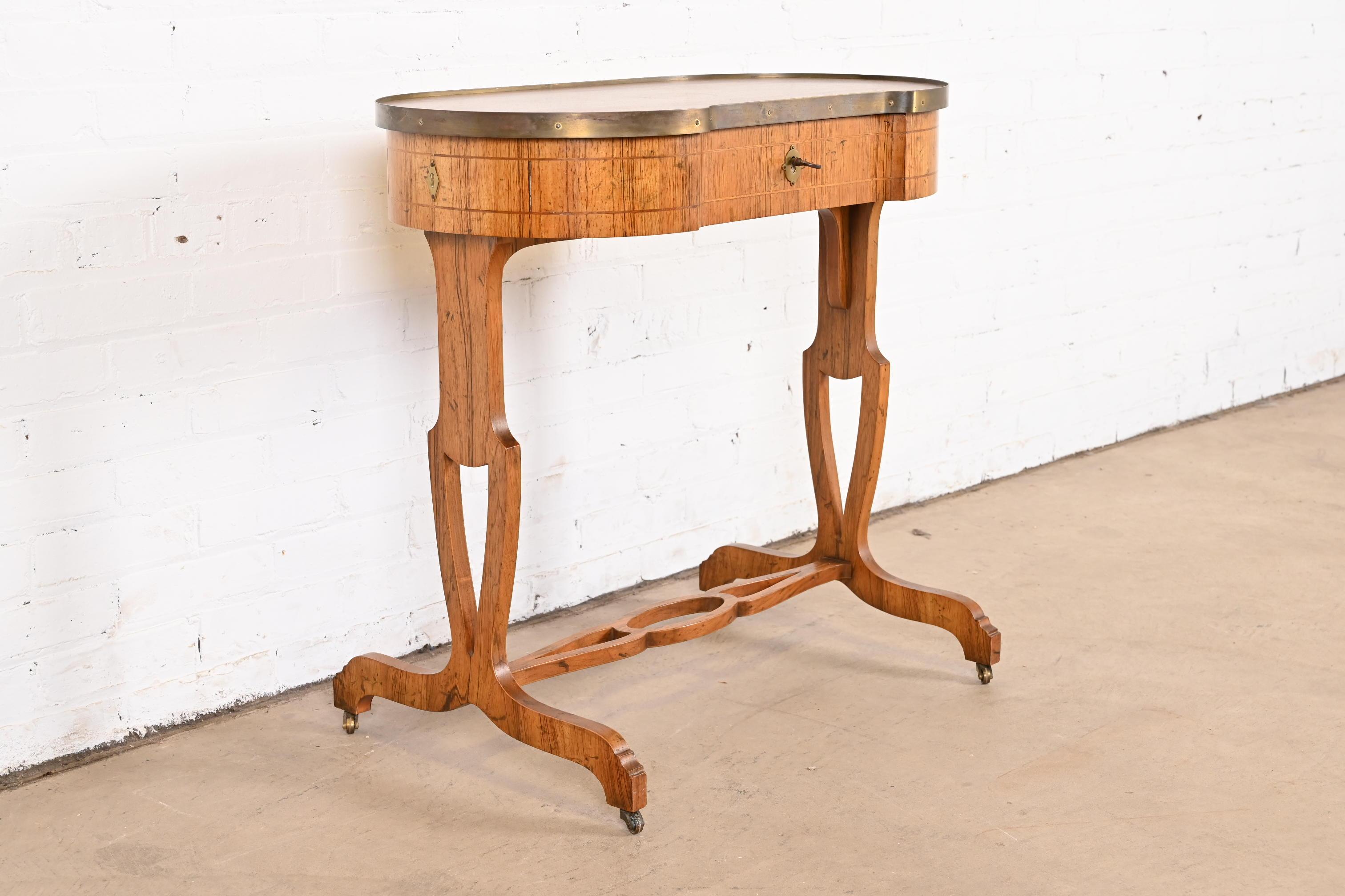 A gorgeous English Regency style console table, entry table, or petite ladies writing desk

By Baker Furniture

USA, Circa 1960s

Rosewood, with satinwood string inlay, and original brass hardware.

Measures: 30