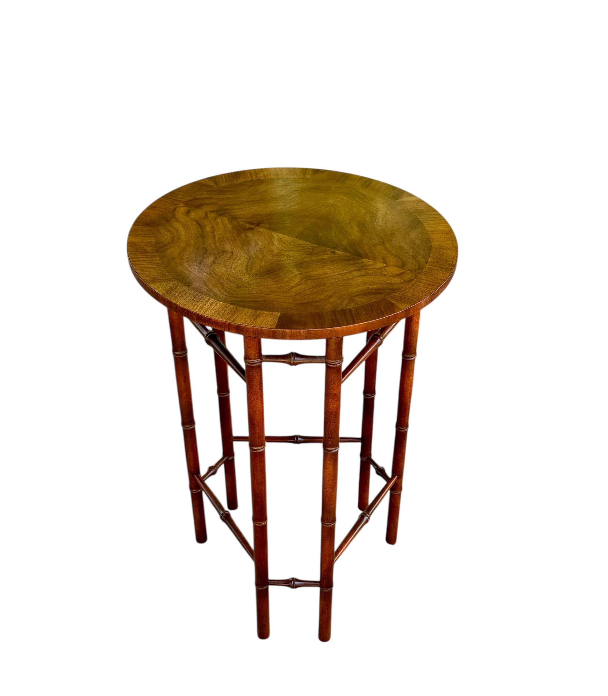Questo elegante tavolino in finto bambù in noce di Baker Furniture Company è un bellissimo esempio di artigianato classico di metà secolo con un tocco di cineseria. Il piano rotondo del tavolo presenta un'impiallacciatura di noce riccamente venata e