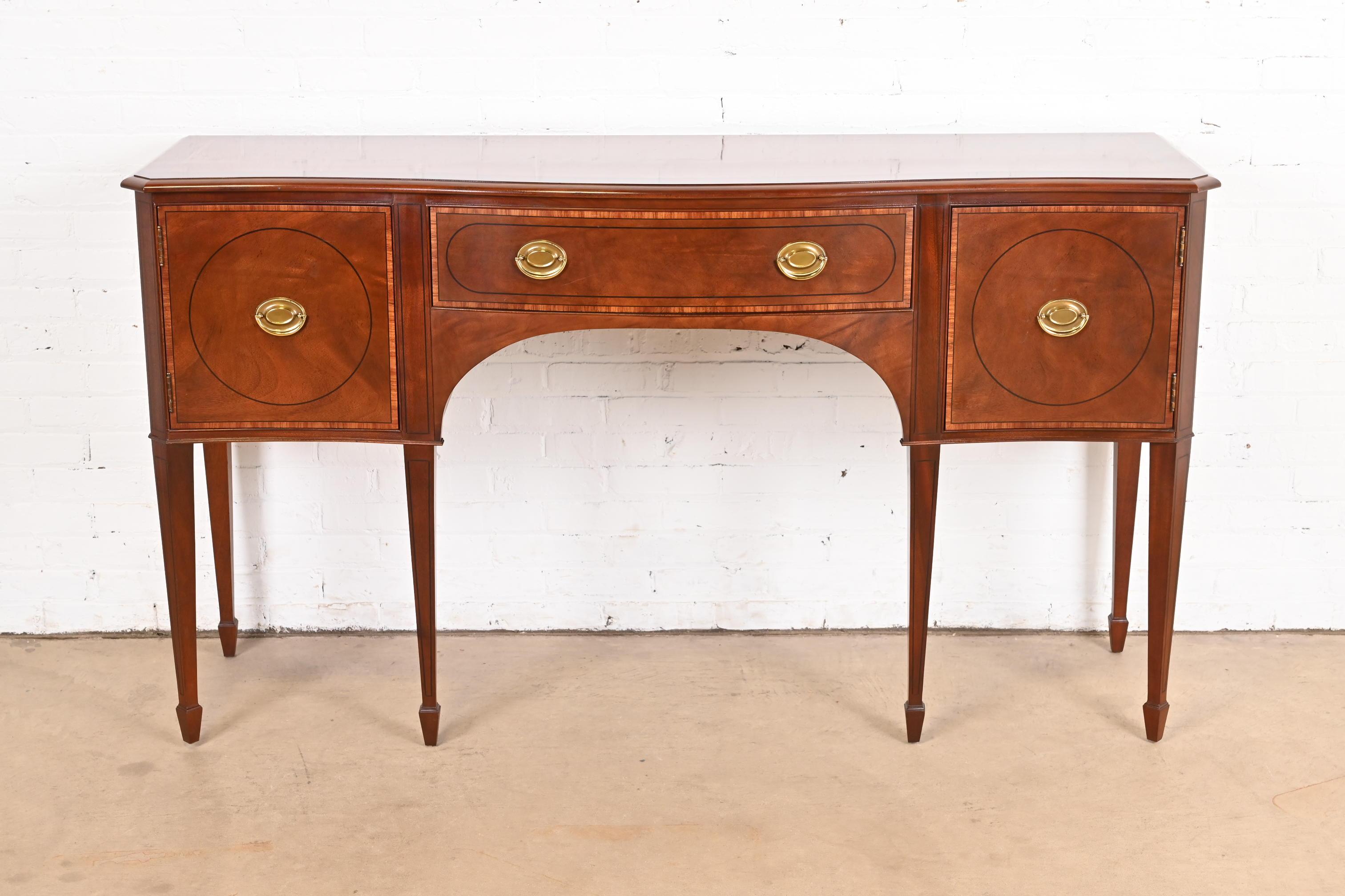 A gorgeous Federal or Hepplewhite style sideboard, credenza, or console

By Baker Furniture

USA, Circa Late 20th Century

Mahogany, with inlaid satinwood banding and ebony string inlay, and original brass hardware.

Measures: 68.25