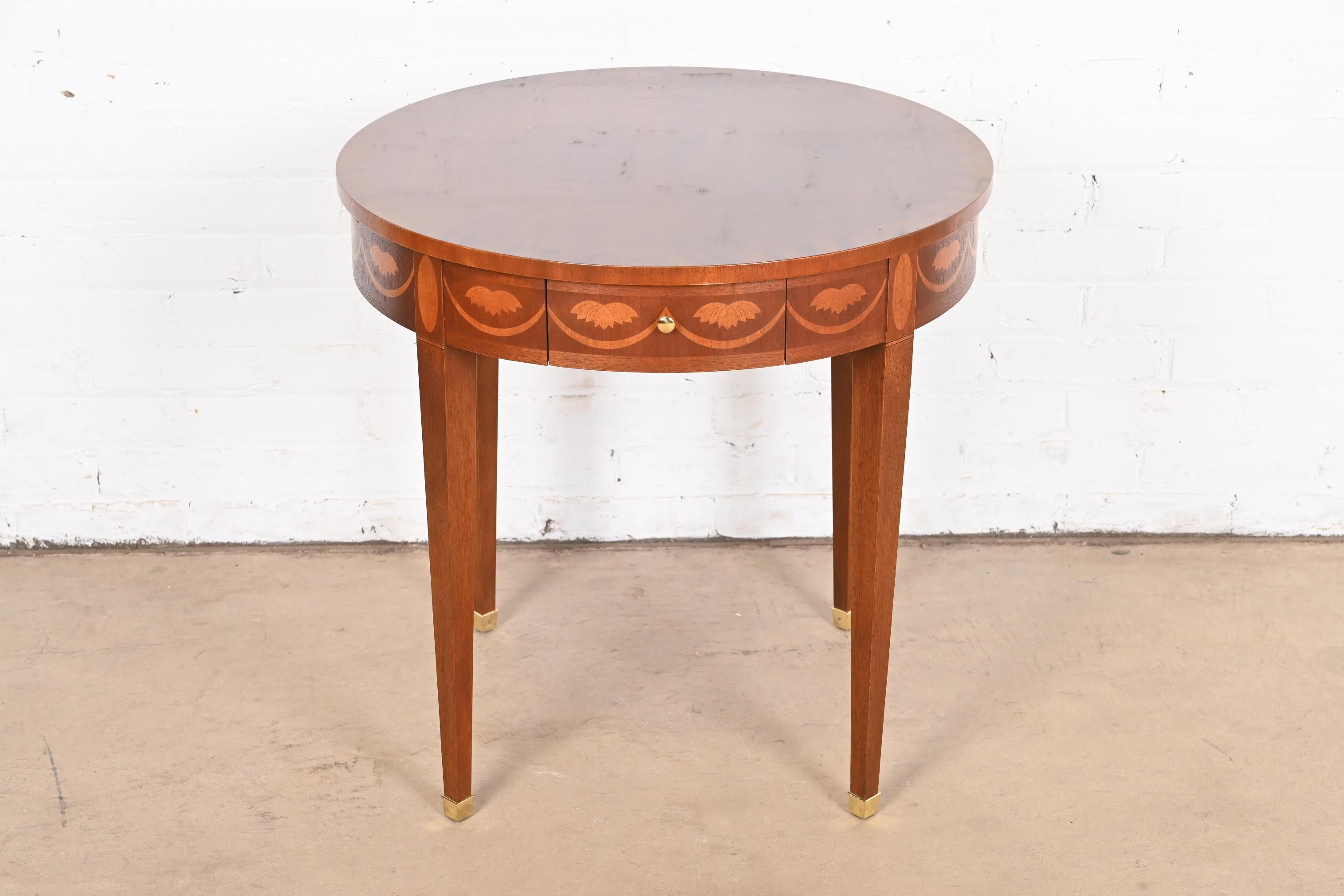A gorgeous Federal or Hepplewhite style tea table or occasional side table

By Baker Furniture

USA, Late 20th Century

Mahogany, with beautiful satinwood inlaid marquetry, original brass hardware, and brass-capped feet.

Measures: 25.5