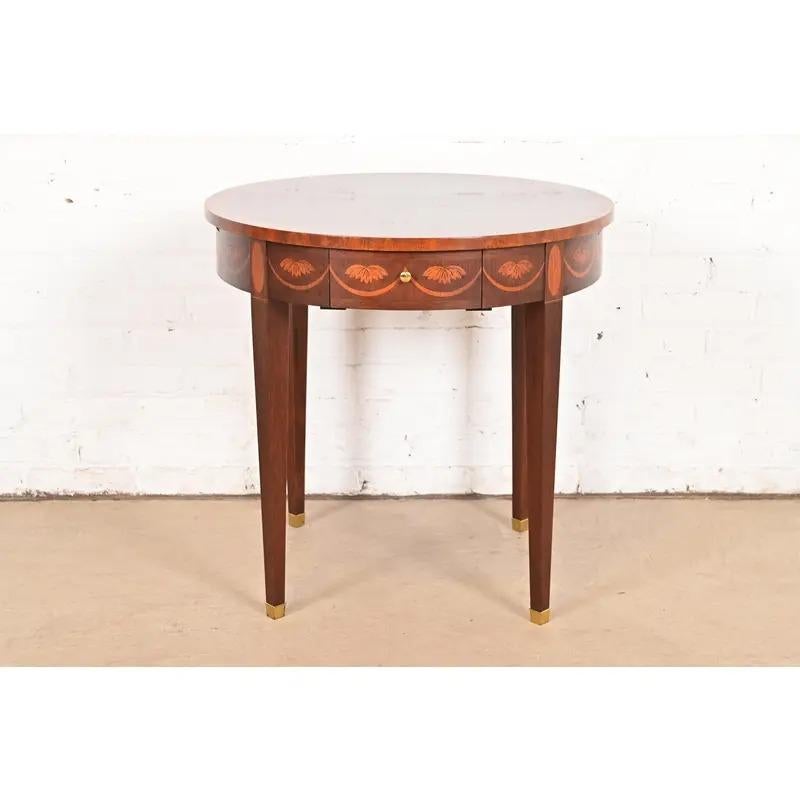 A gorgeous Federal or Hepplewhite style tea table or occasional side table

By Baker Furniture

USA, Late 20th Century

Mahogany, with beautiful satinwood inlaid marquetry, original brass hardware, and brass-capped feet.

Measures: 25.25