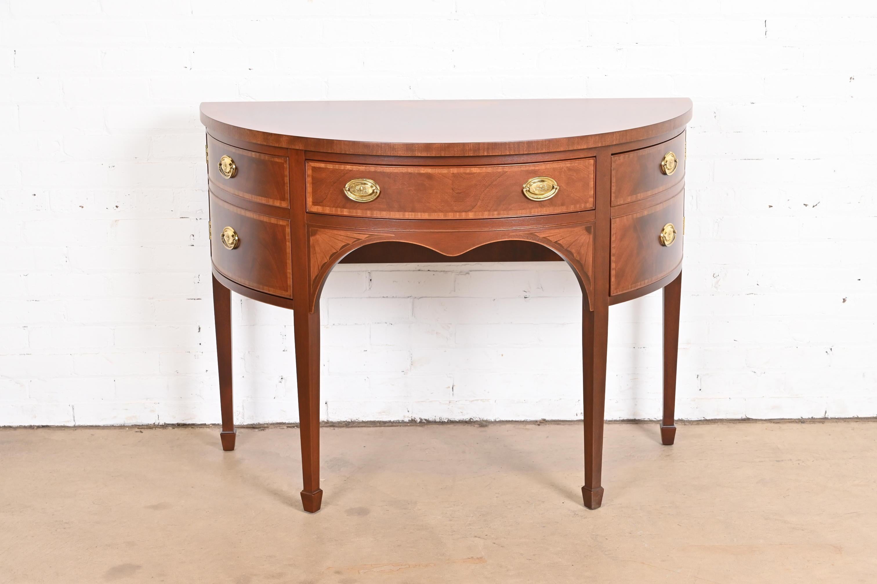 An exceptional Federal or Hepplewhite style demilune cabinet or sideboard

By Baker Furniture

USA, Circa 1980s

Flame mahogany, with satinwood banding and inlay, and original brass hardware.

Measures: 45.25