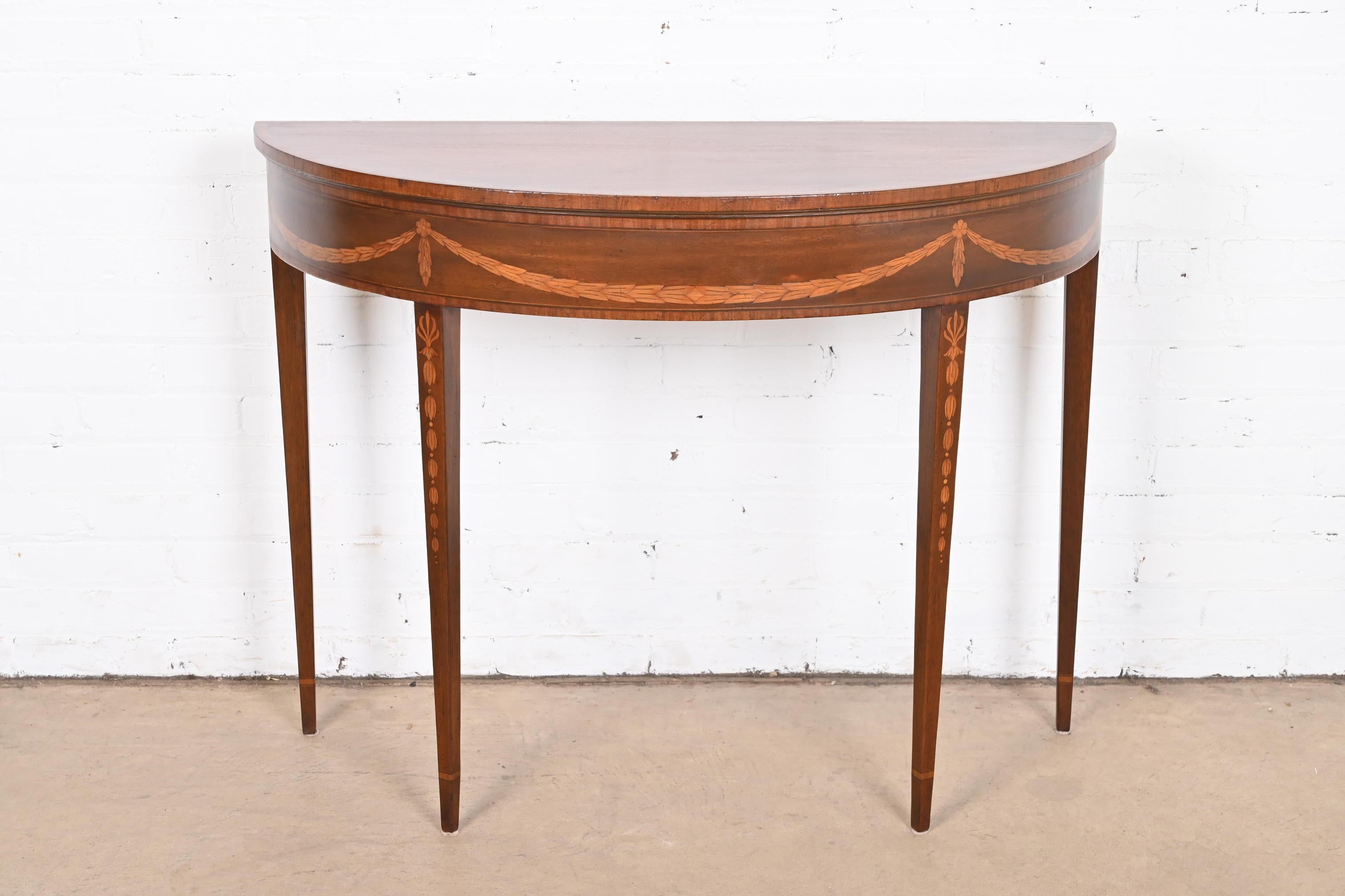 A gorgeous Federal or Hepplewhite style demilune console table, sofa table, or entry table

By Baker Furniture

USA, circa Mid-20th Century

Mahogany, with inlaid satinwood floral marquetry.

Measures: 40.5