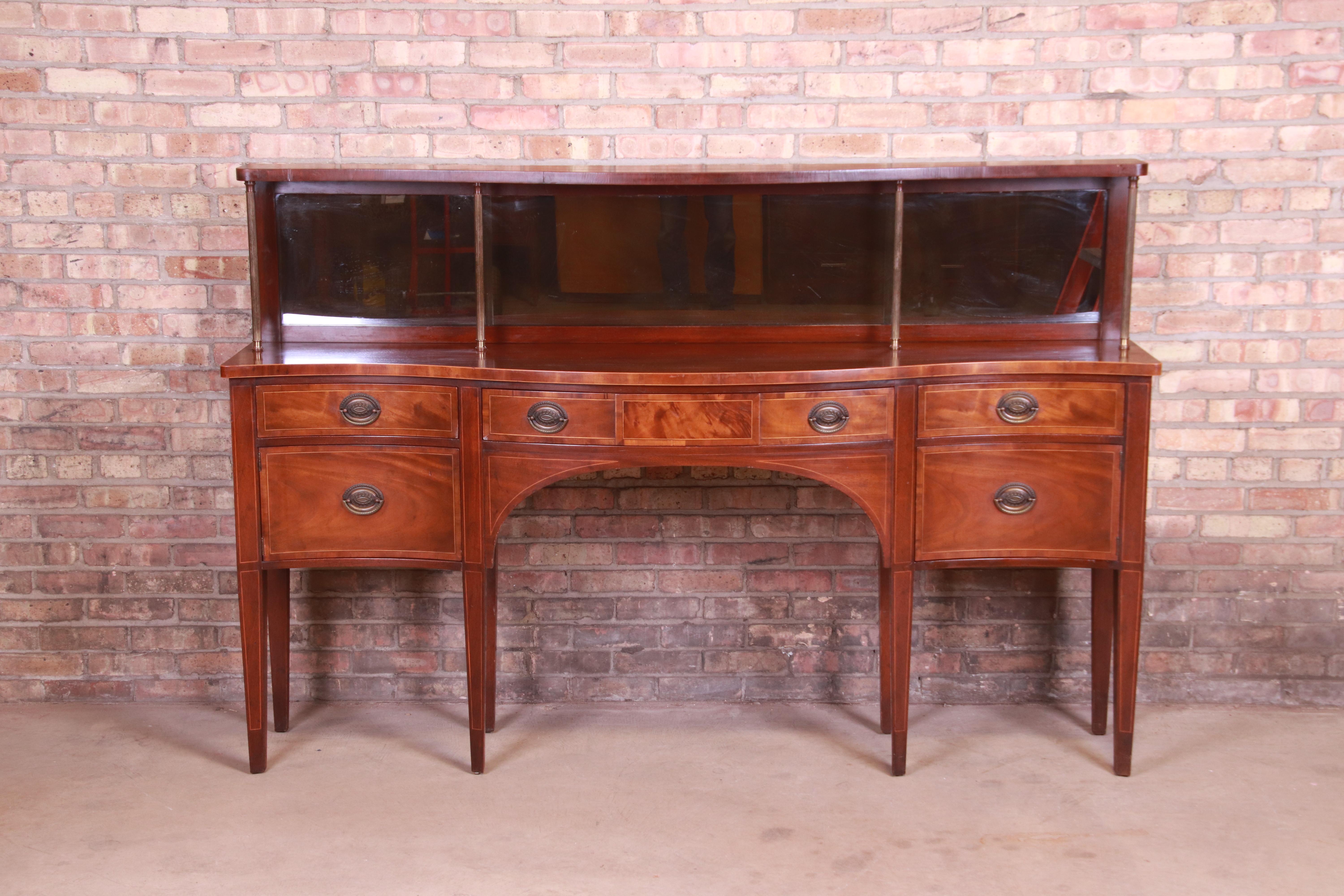 An exceptional Federal style sideboard, credenza, or bar cabinet

By Baker Furniture,

USA, circa 1940s

Mahogany, with satinwood string inlay, mirrored backslash, and original brass hardware and columns.

Measures: 78.13