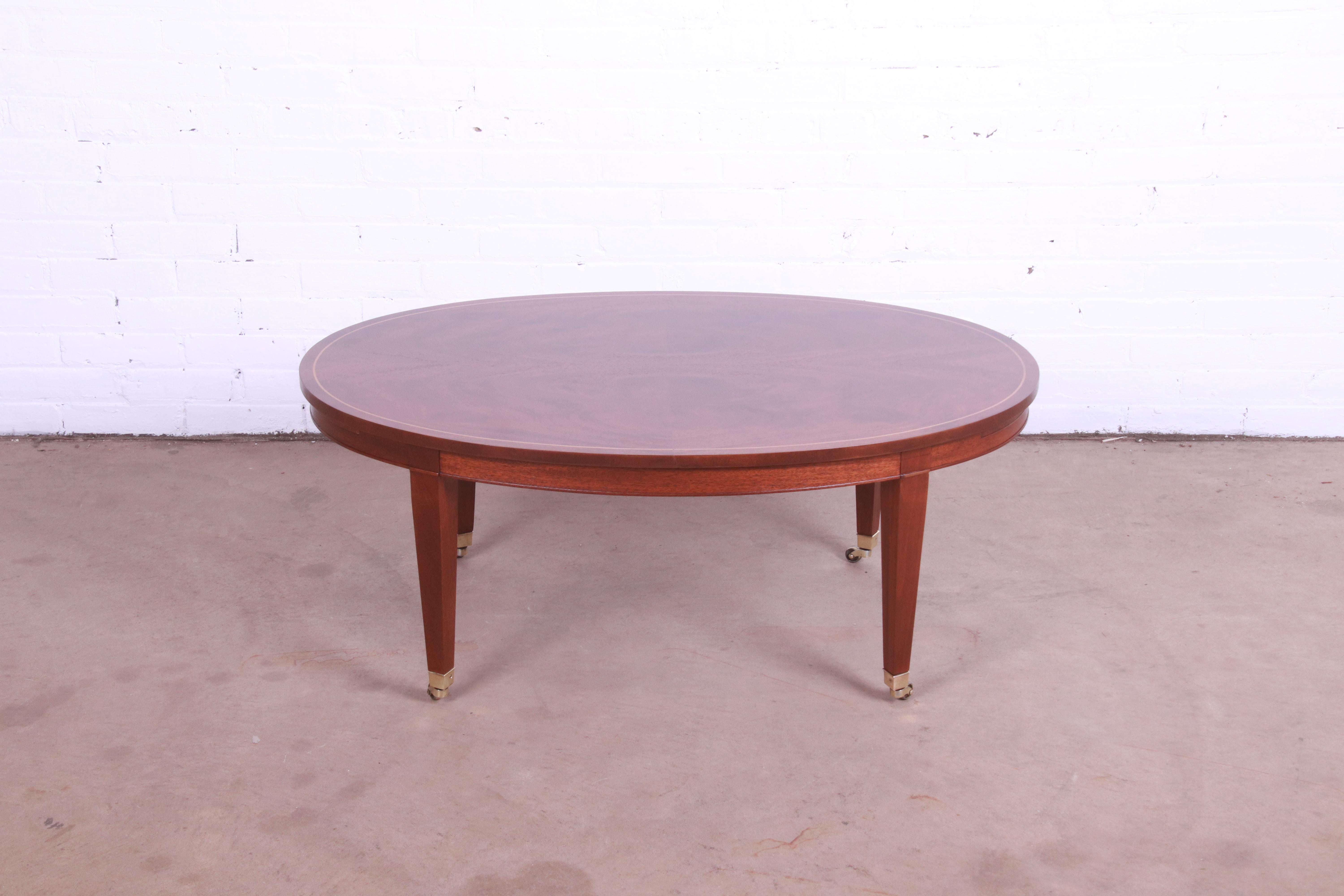 An exceptional Federal style coffee table with extension trays

By Baker Furniture

USA, circa 1980s

Book-matched mahogany, with satinwood string inlay, brass hardware, and brass casters.

Measures: 42
