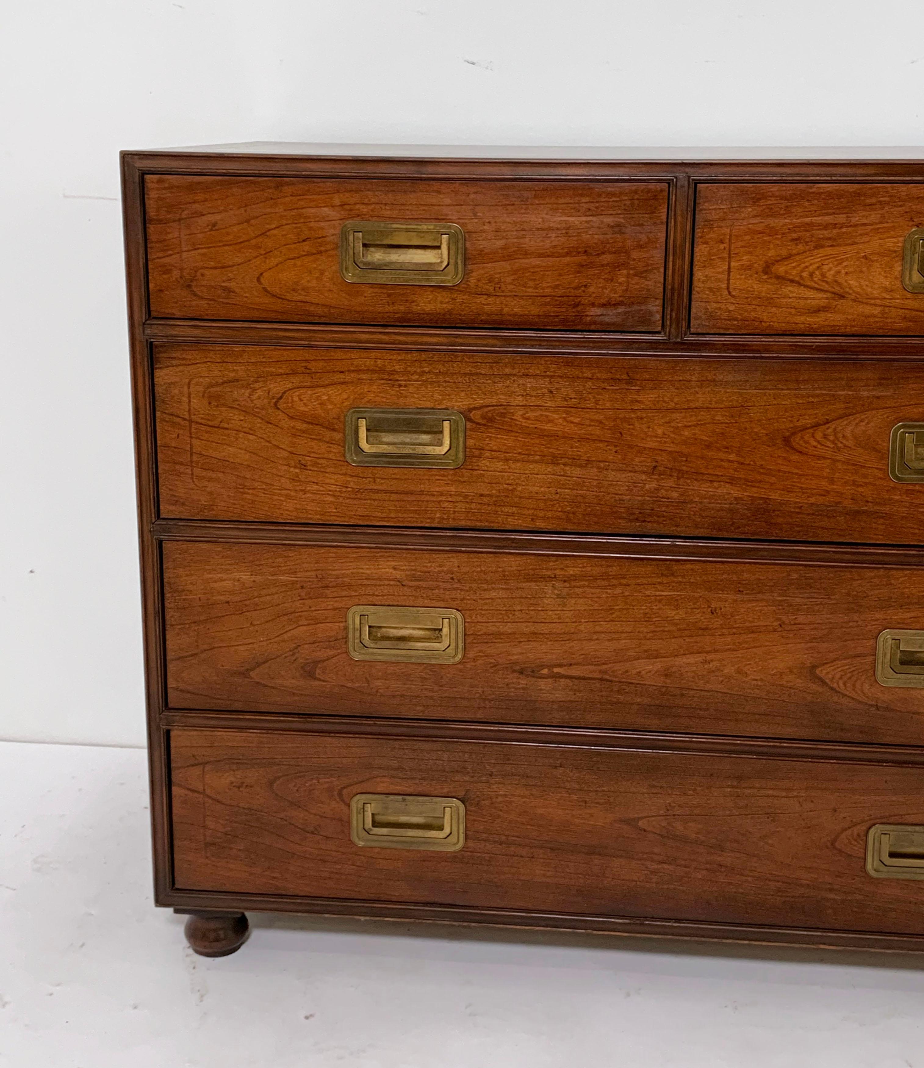 A rare form fine Campaign chest of five drawers by Baker, circa 1940s. This early walnut example features mahogany banding and bun feet.