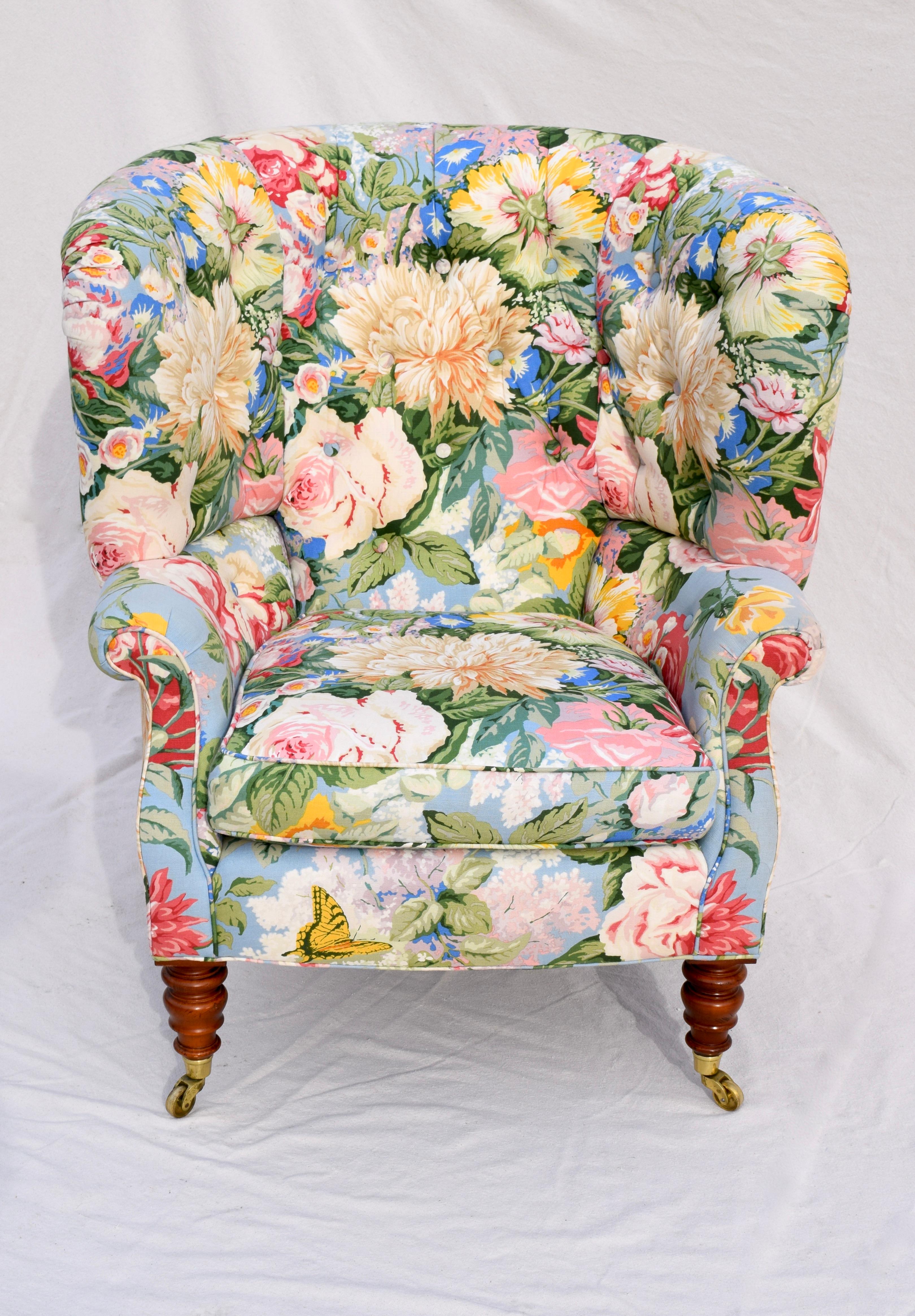 An exceptional cottage chic Baker Furniture Company wingback lounge chair. Features include enveloping, curved and tufted clamshell form on brass casters upholstered in vibrant multi floral cotton upholstery with a linen feel. Nice mid-size with