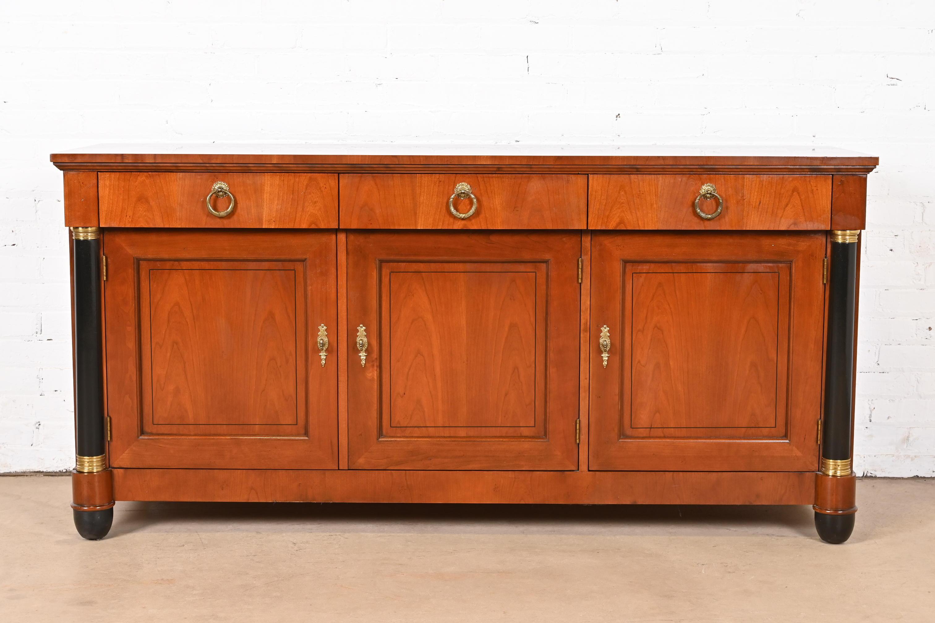 Magnifique buffet, crédence ou meuble de bar de style Empire ou néoclassique français.

Par Baker Furniture

USA, Circa 1980

Bois de cerisier sculpté, avec colonnes et pieds ébénisés, et quincaillerie originale en laiton. Les étagères sont