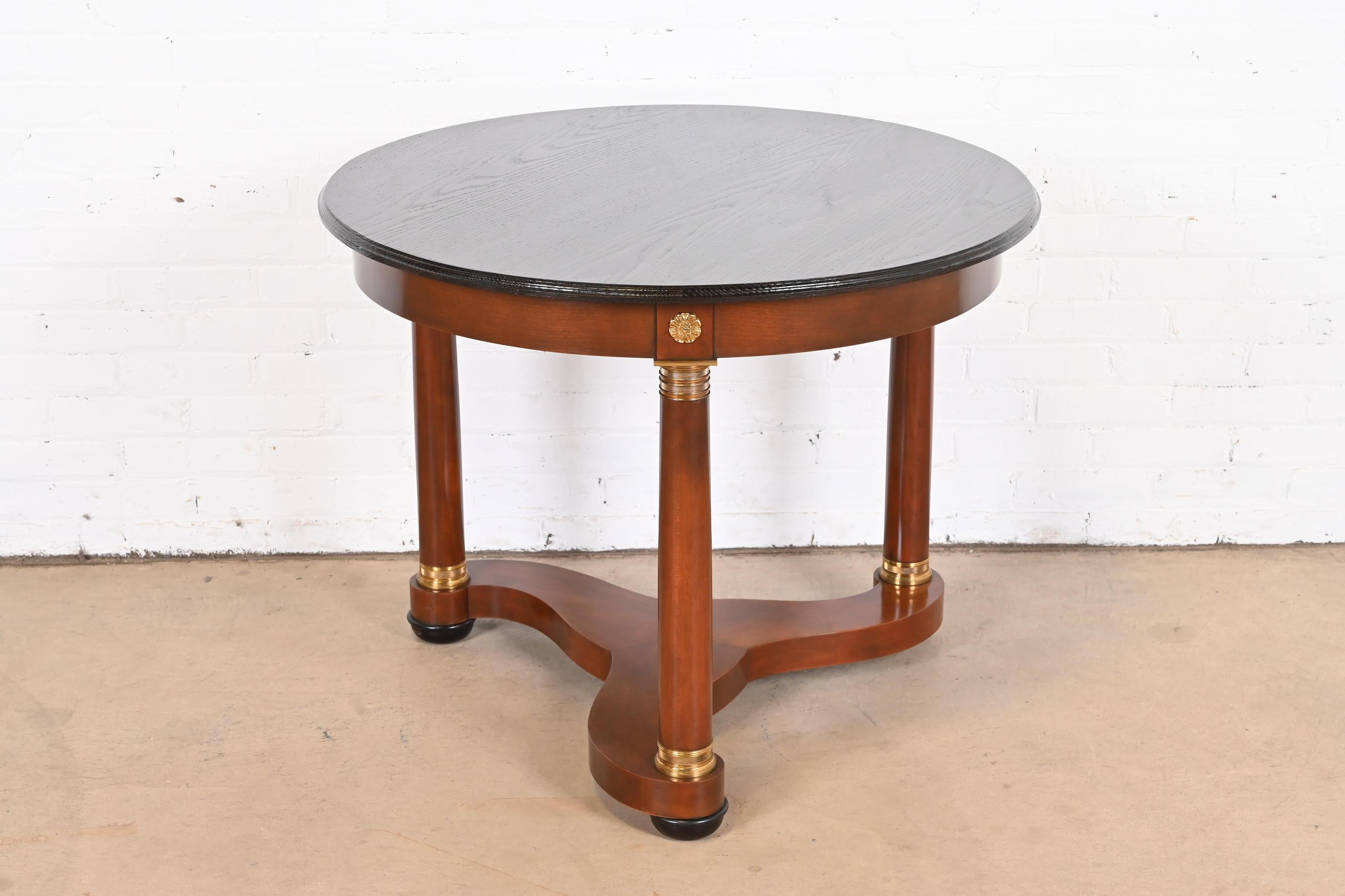 An elegant French Empire or Neoclassical tea table or center table

By Baker Furniture

USA, Late 20th Century

Cherry wood base, with mounted brass accents, and ebonized wood top.

Measures: 36.38