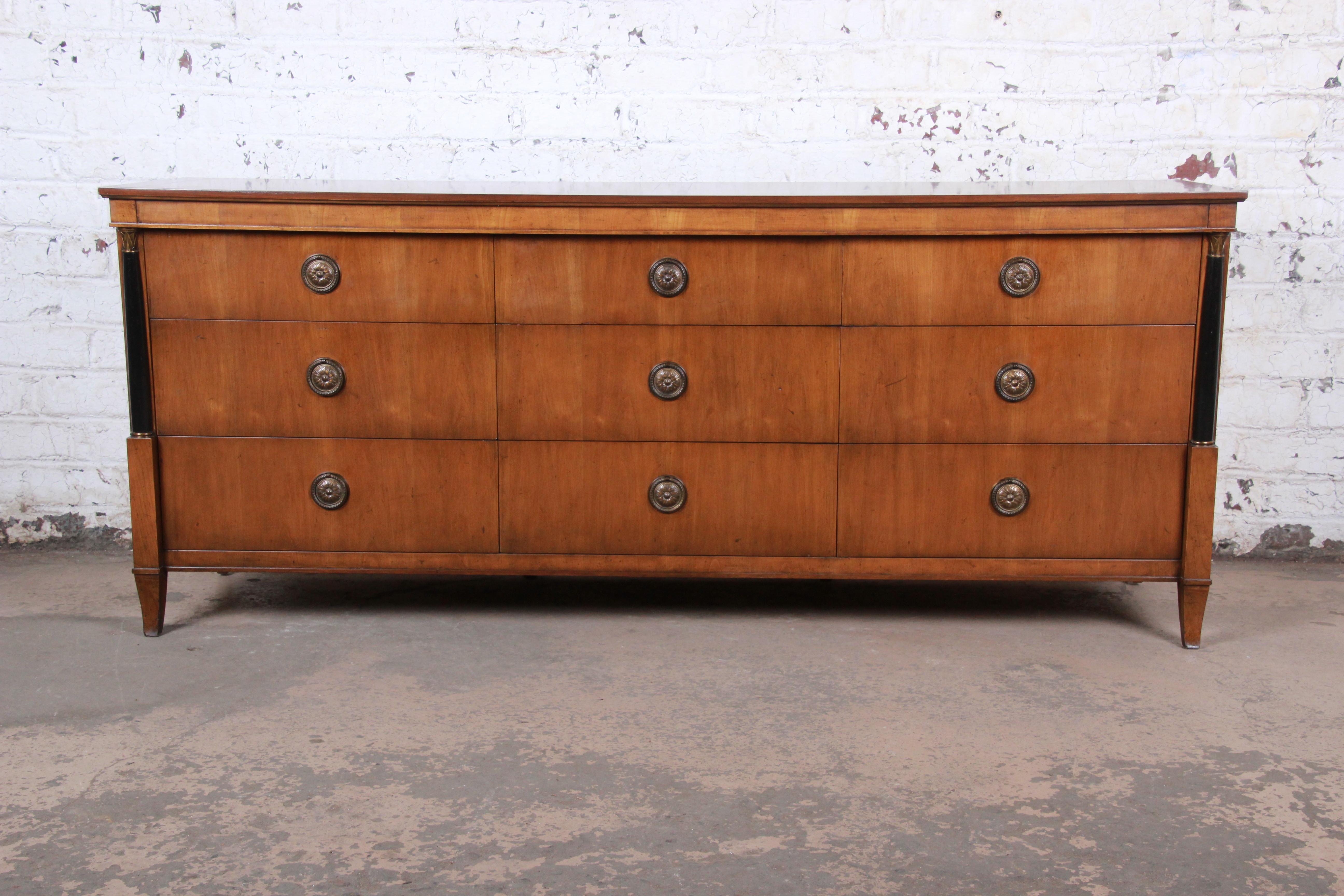 An exceptional French Empire style long dresser or credenza

By Baker Furniture

USA, circa 1960s

Bookmatched cherry and ebonized wood and brass hardware and accents

Measures: 76
