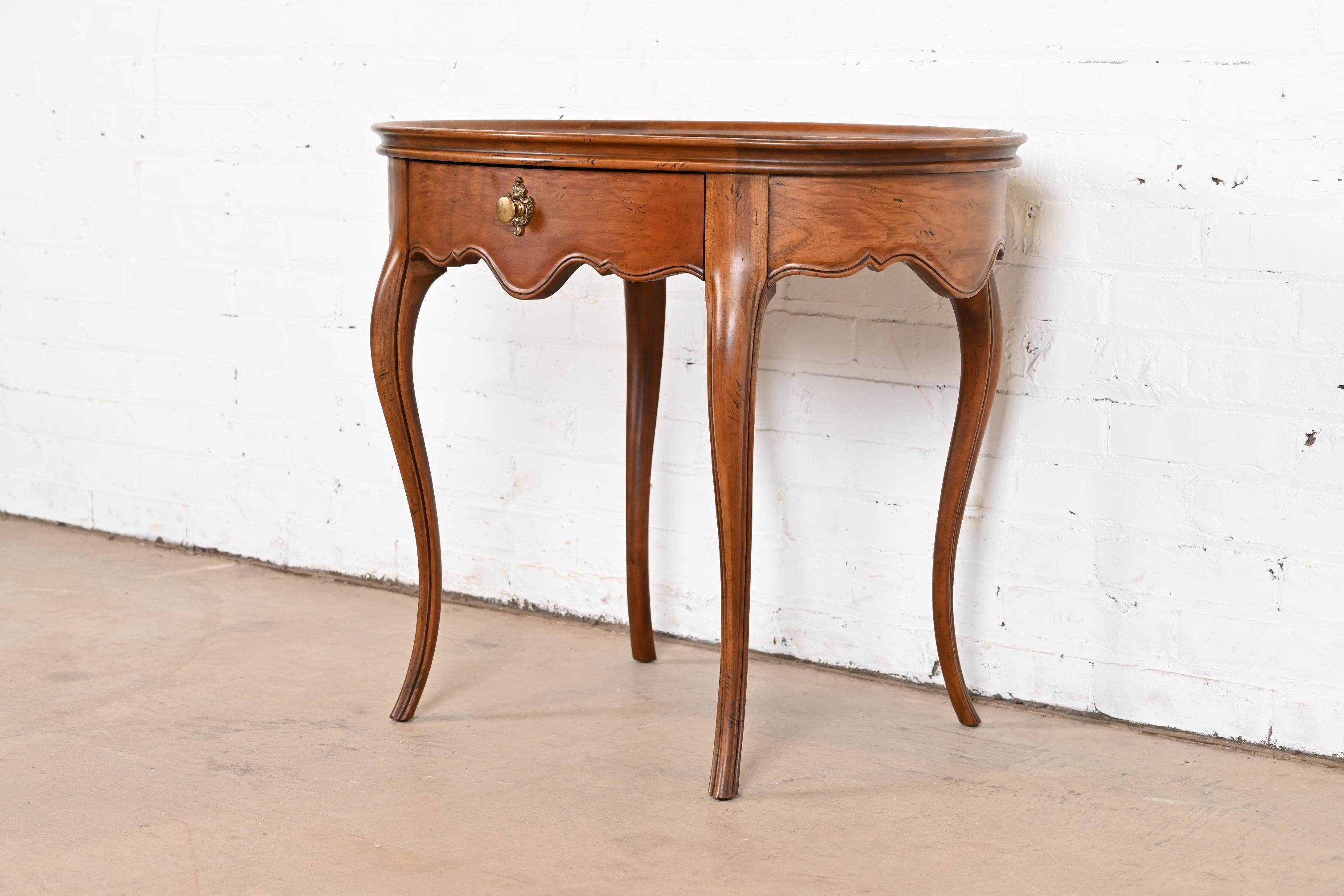 A beautiful French Provincial Louis XV style one-drawer nightstand, tea table, or occasional side table

By Baker Furniture

USA, Circa 1960s

Carved walnut, with gorgeous book-matched burled walnut top, and original brass hardware.

Measures: