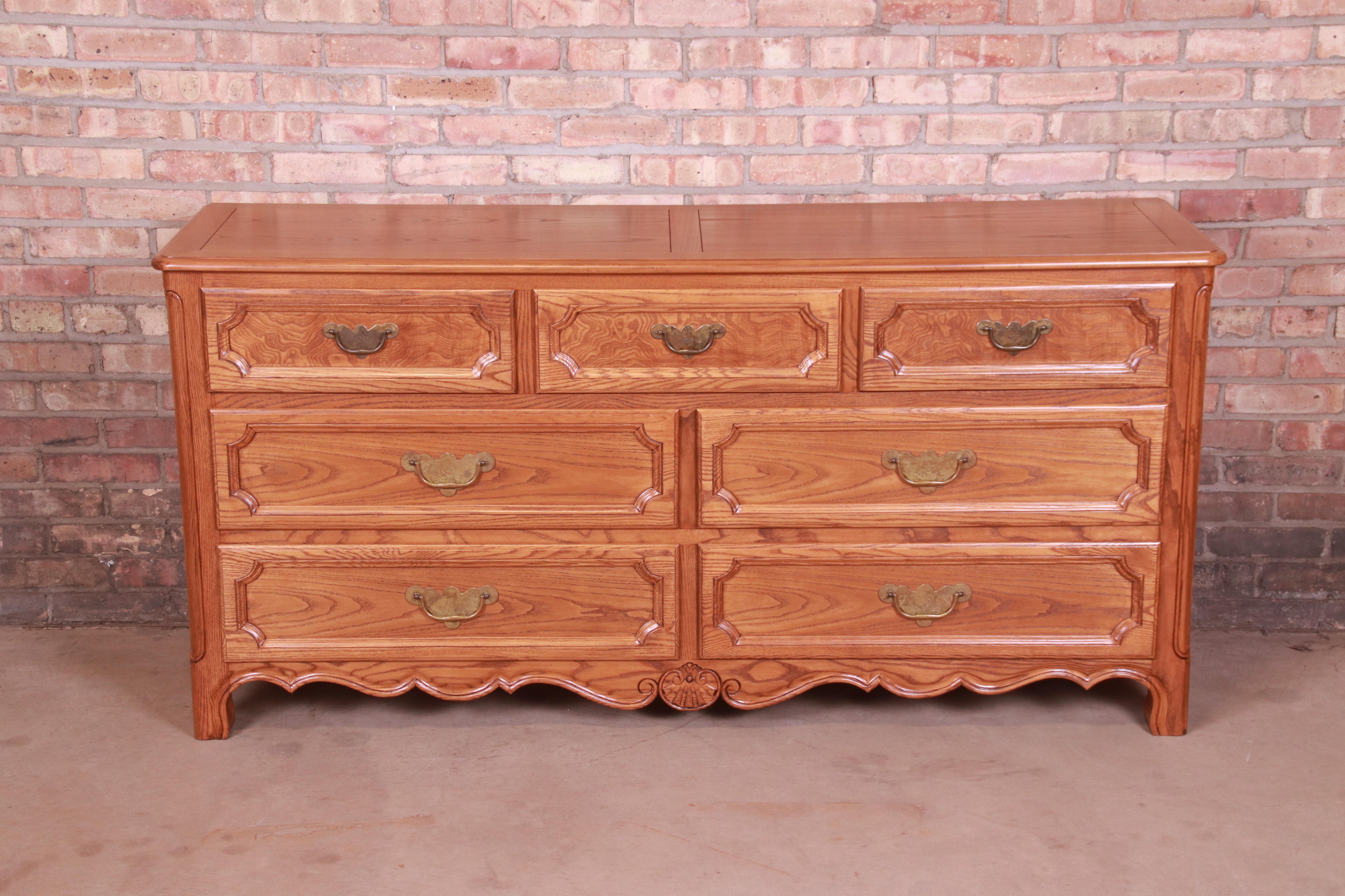 An exceptional French Provincial style seven-drawer dresser or credenza

By Baker Furniture

USA, Circa 1960s

Carved oak, with burl wood drawer fronts and original brass hardware.

Measures: 66.25