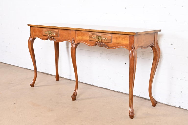 A gorgeous French Provincial Louis XV style console table or sofa table

By Baker Furniture

USA, Circa 1960s

Book-matched burled walnut top with burled olive wood banding, carved solid cherry wood cabriole legs, and original brass