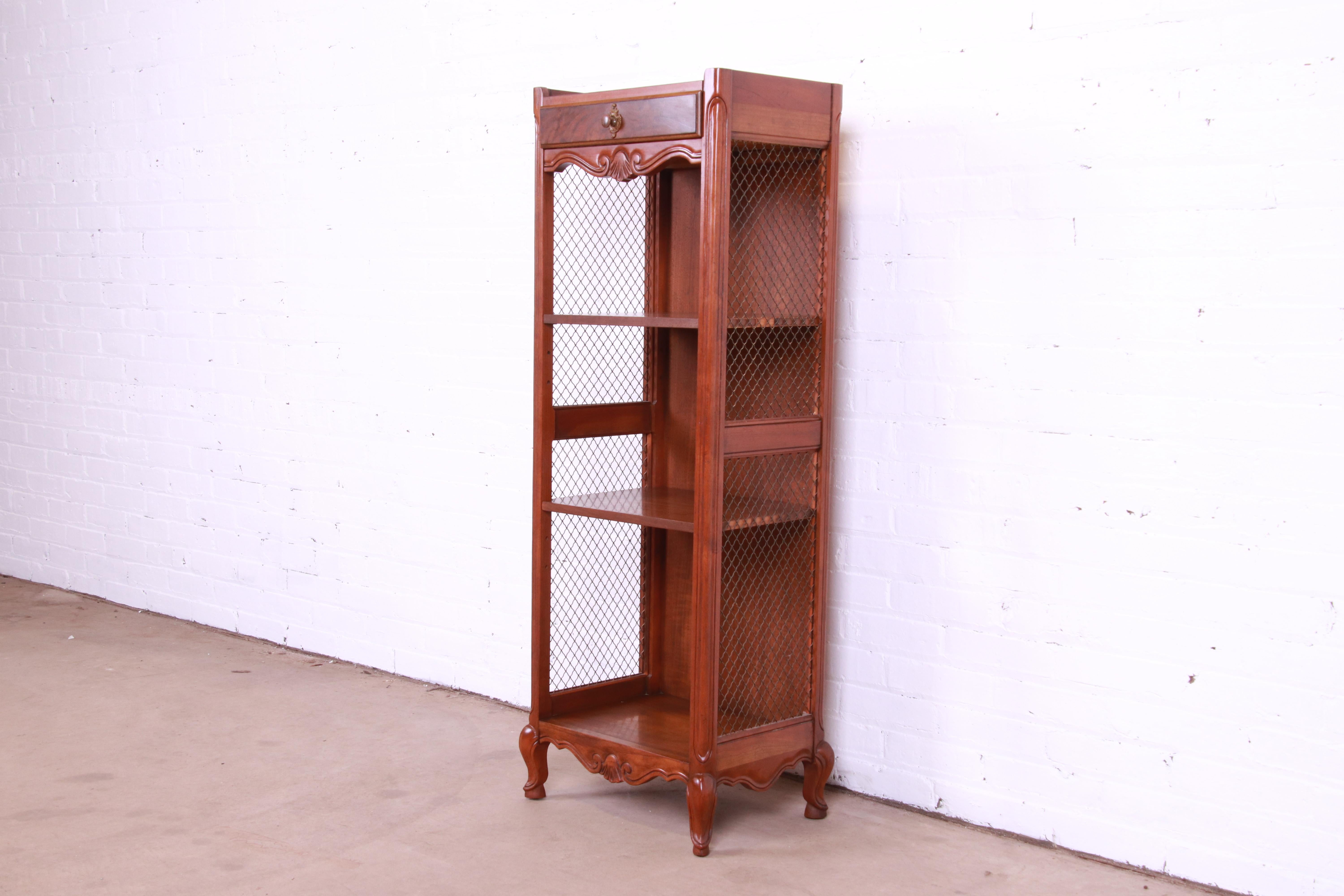 A beautiful French Provincial Louis XV style bookcase or etagere

By Baker Furniture

USA, Circa 1980s

Carved walnut, with burled walnut drawer front and original brass hardware.

Measures: 17