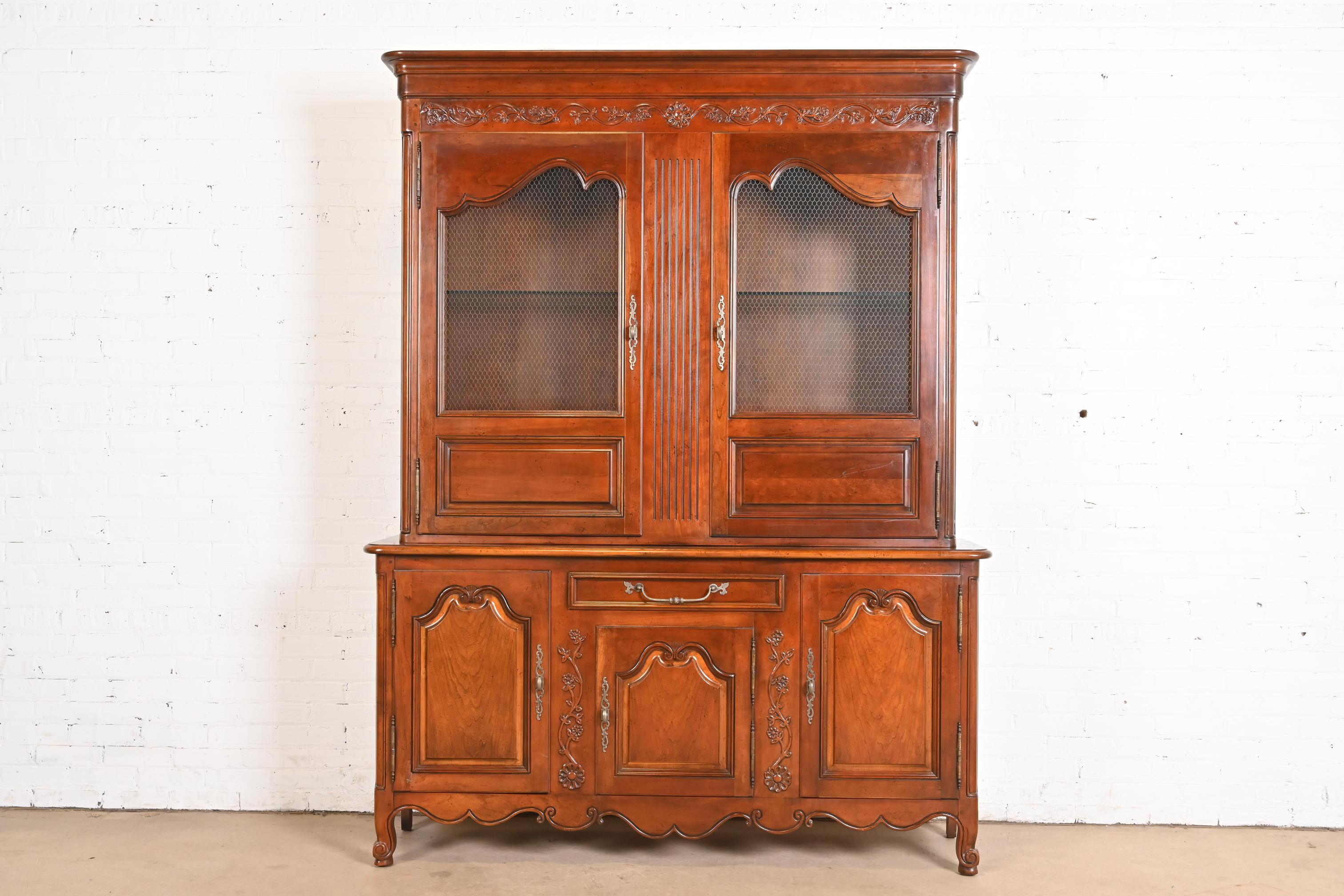 A gorgeous French Country or French Provincial Louis XV style lighted breakfront bookcase cabinet or dining cabinet

By Baker Furniture

USA, Circa 1980s

Carved solid cherry wood, with original brass hardware. Lights are tested and in working