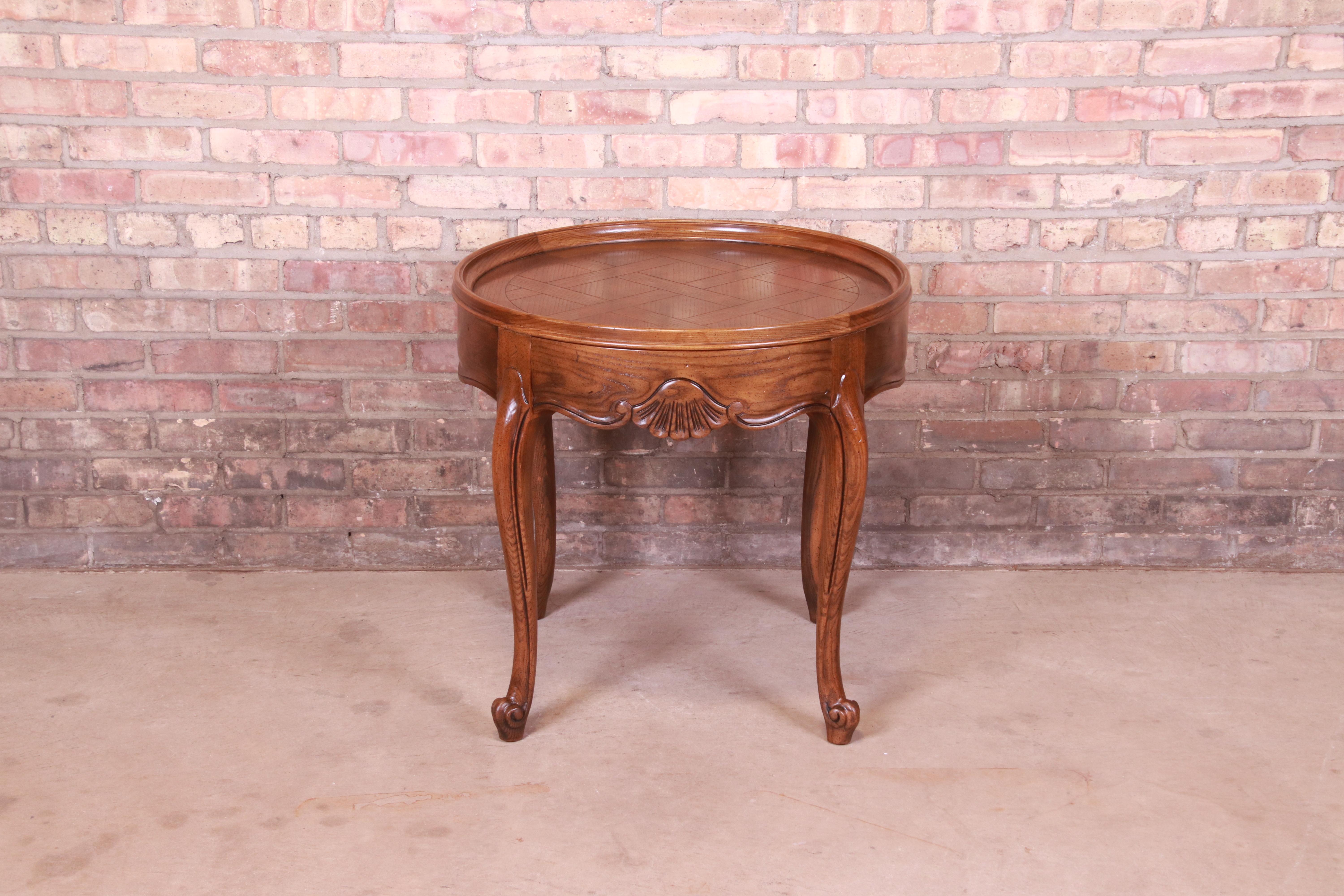 A gorgeous French Provincial Louis XV style occasional side table or tea table

By Baker Furniture

USA, Circa 1960s

Carved oak, with parquetry top.

Measures: 27