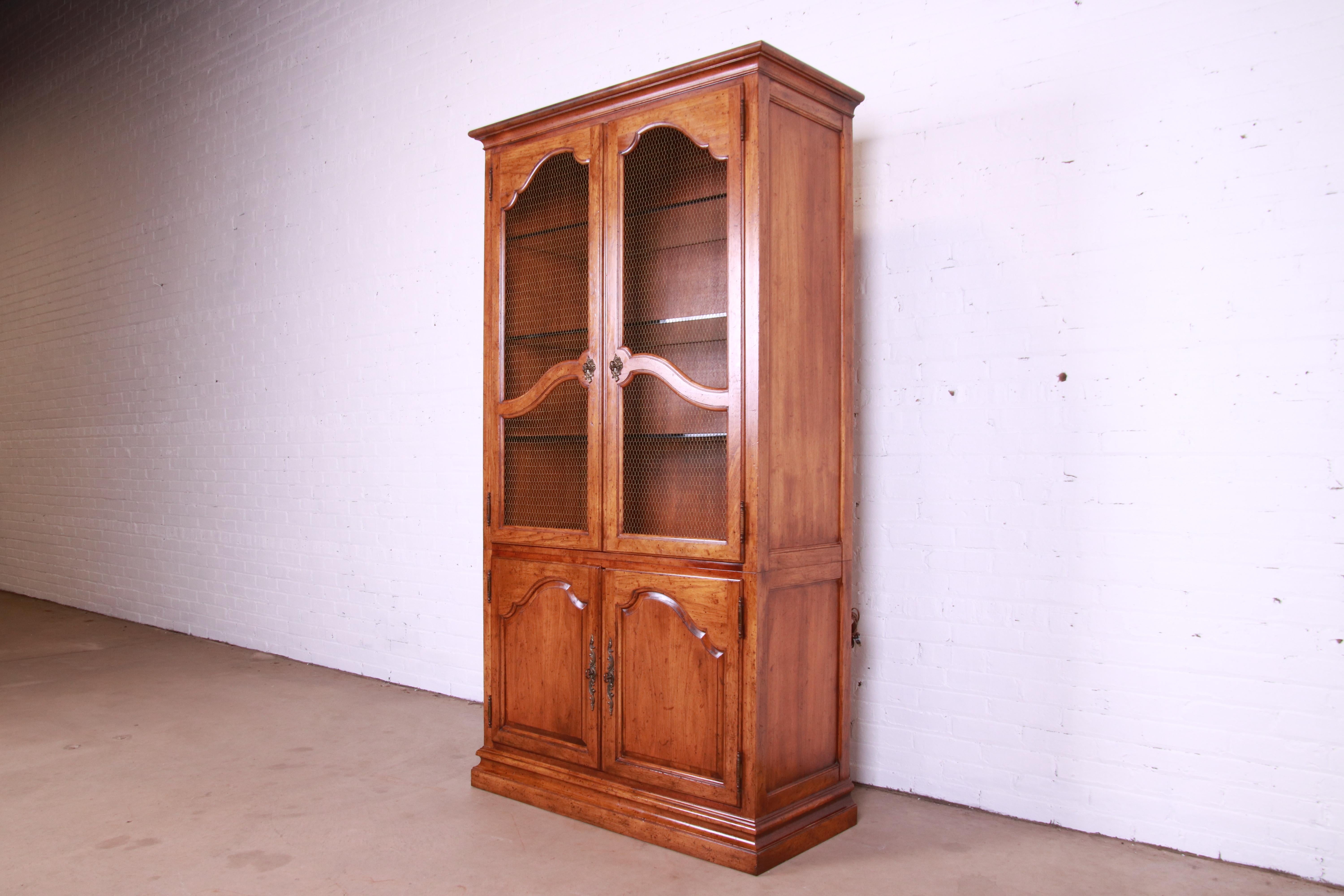 A gorgeous French Provincial Louis XV style lighted bibliotheque bookcase or display cabinet

By Baker Furniture

USA, Circa 1960s

Carved walnut, with original brass hardware.

Measures: 43