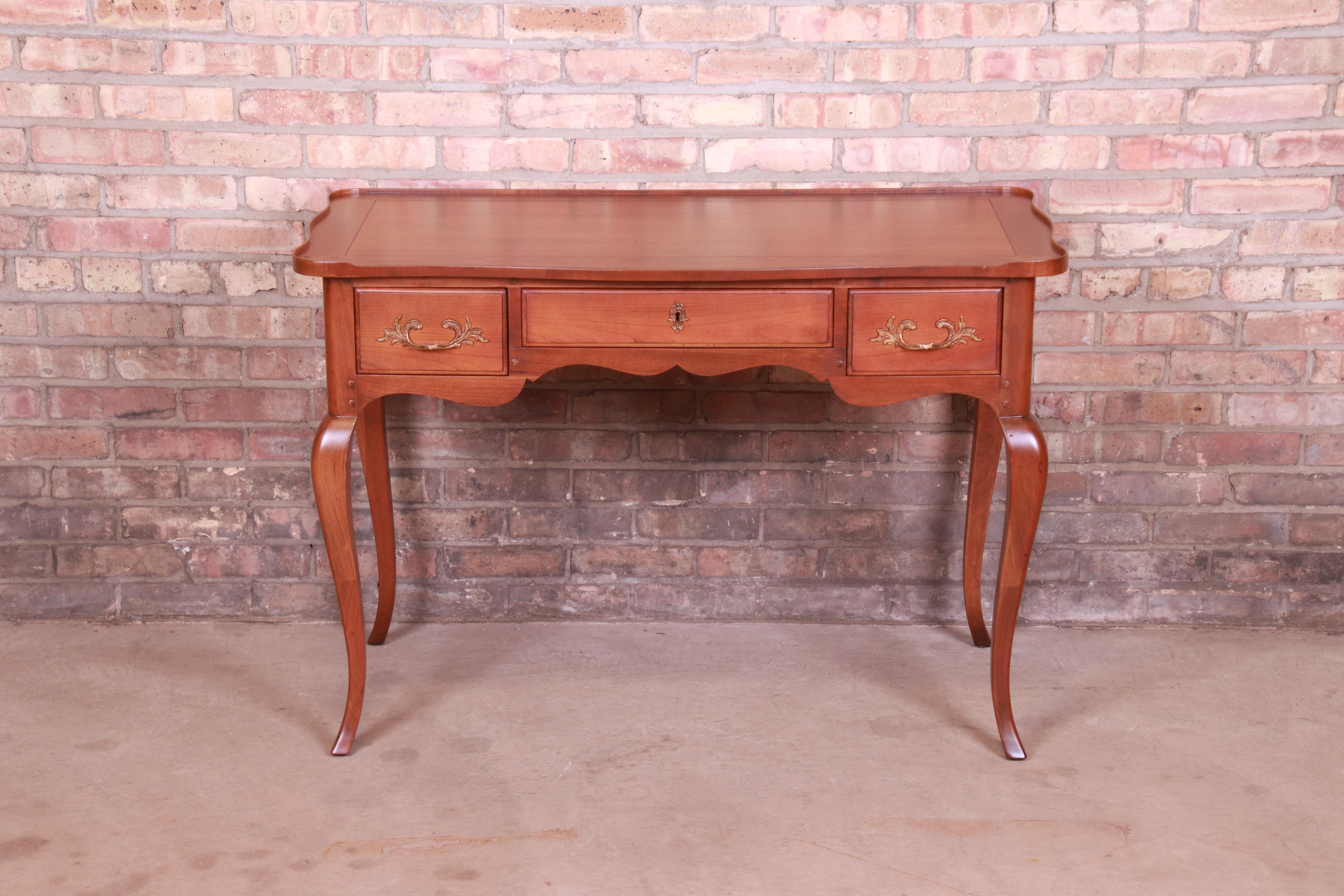 A gorgeous French Provincial Louis XV style writing desk

By Baker Furniture

USA, Circa 1960s

Cherry wood, with original brass hardware. Middle drawer locks, and key is included.

Measures: 43